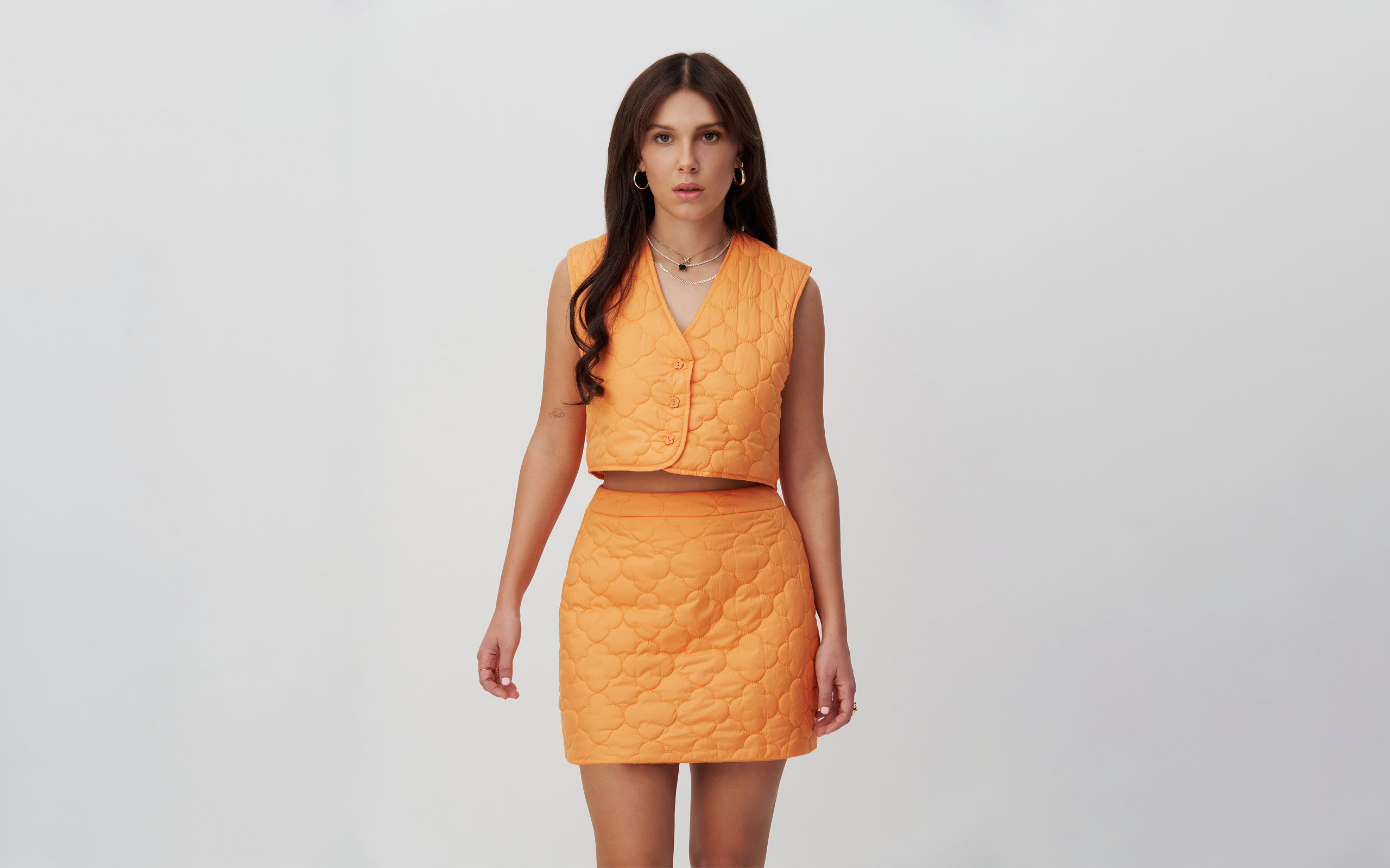 Девушка актриса Милли Бобби Браун в костюме на сером фоне