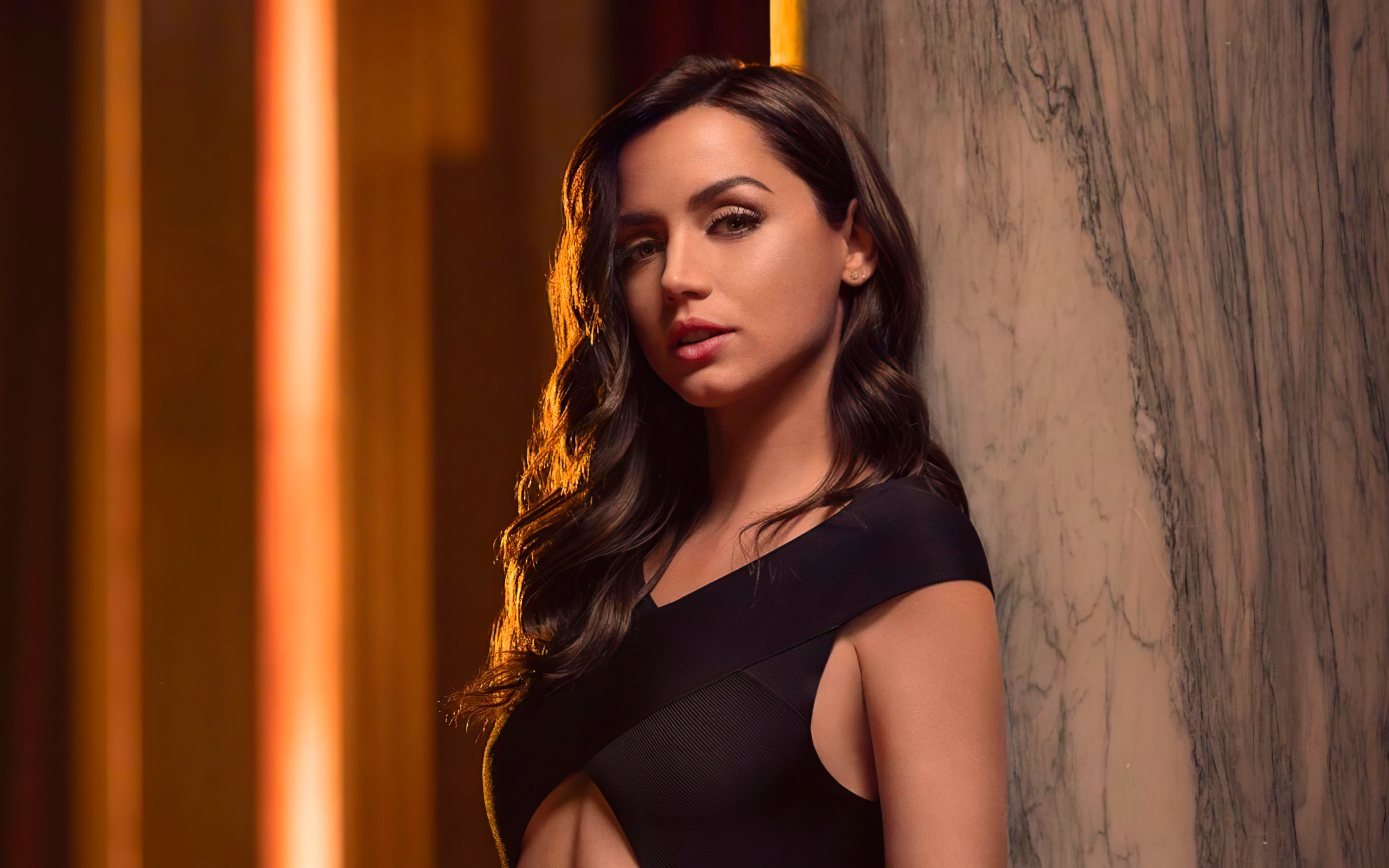 Длинноволосая актриса Ана де Армас стоит у стены