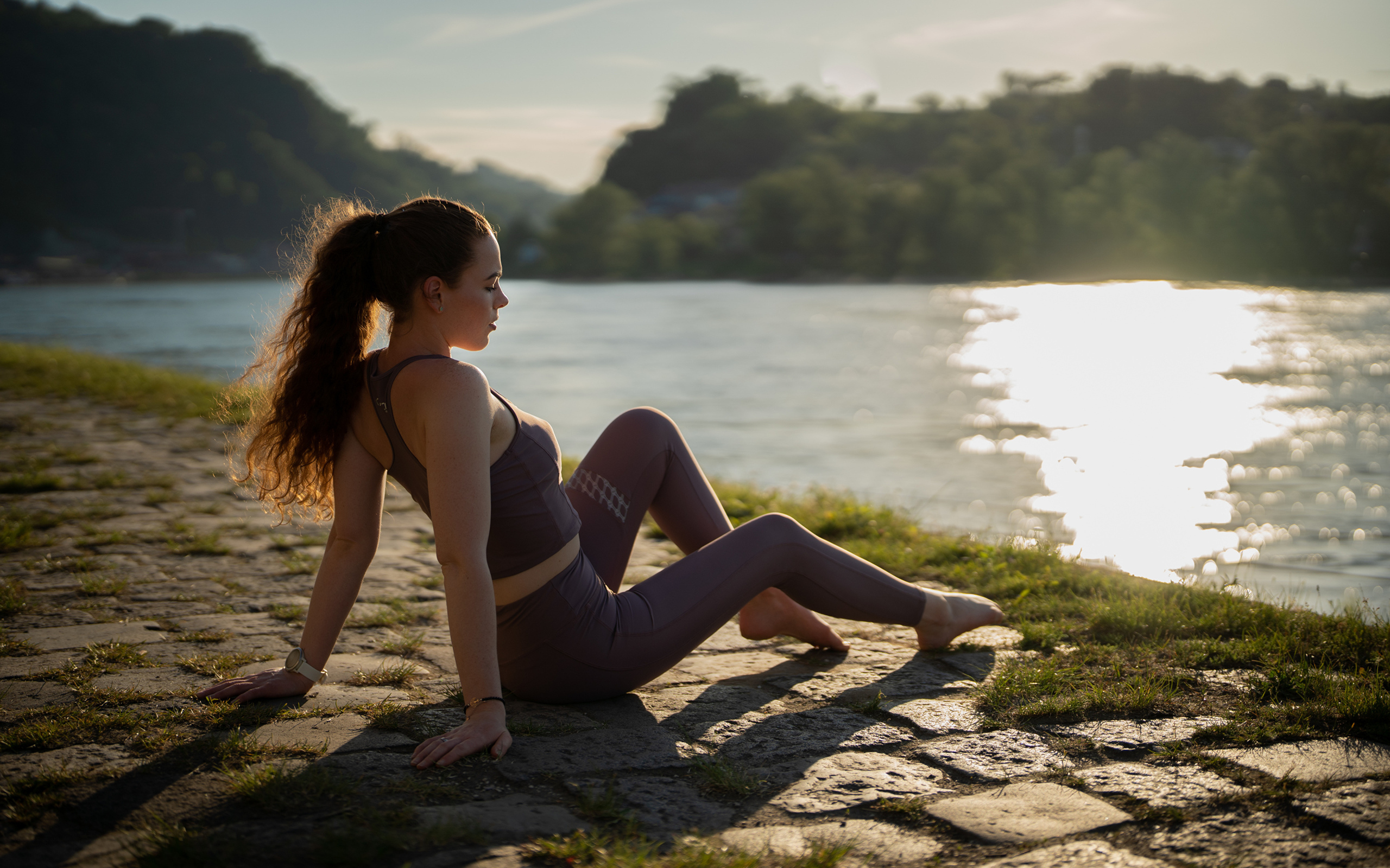 Спортивная девушка сидит на берегу реки