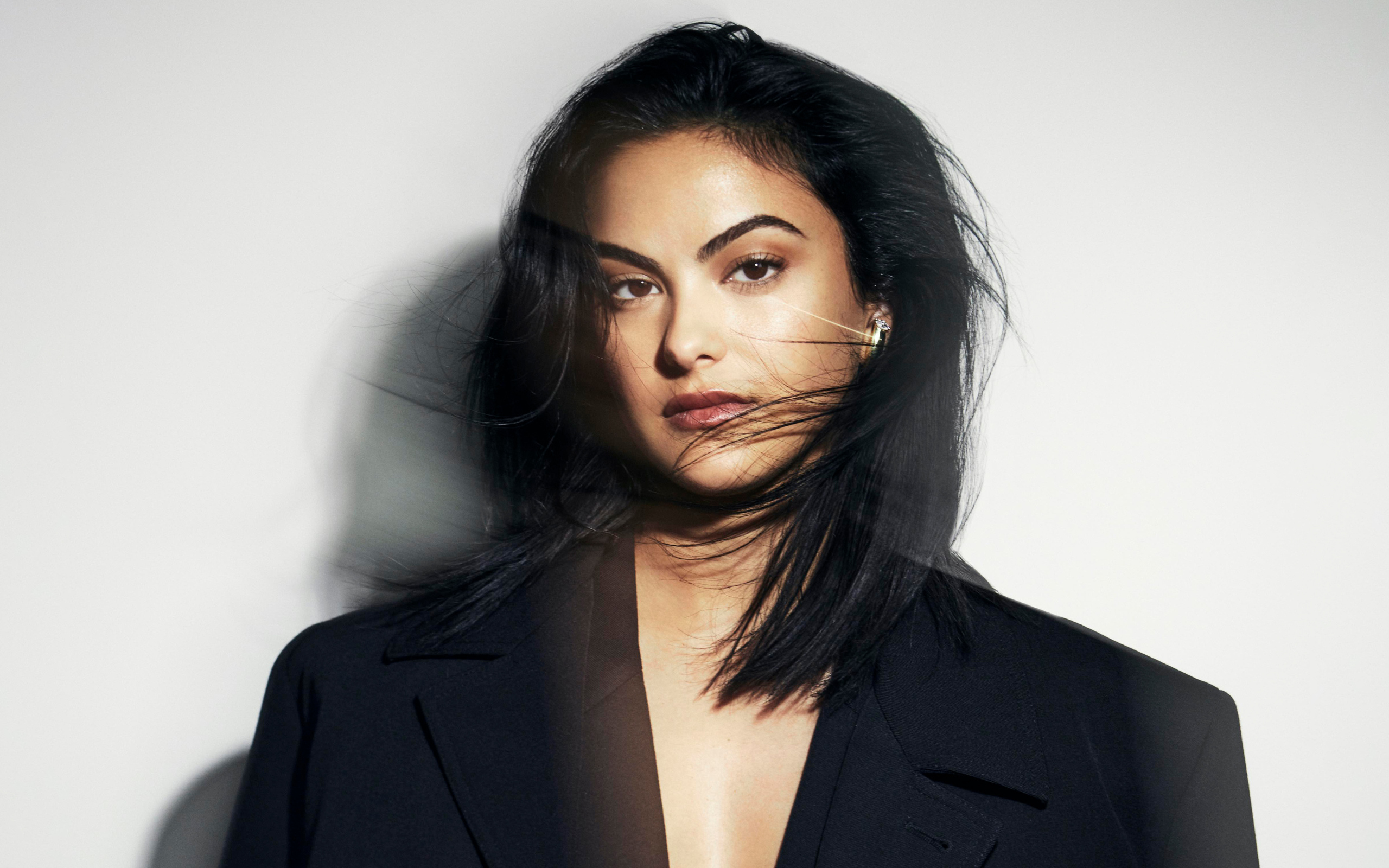 Стильная актриса Камила Мендес в черном пиджаке на сером фоне