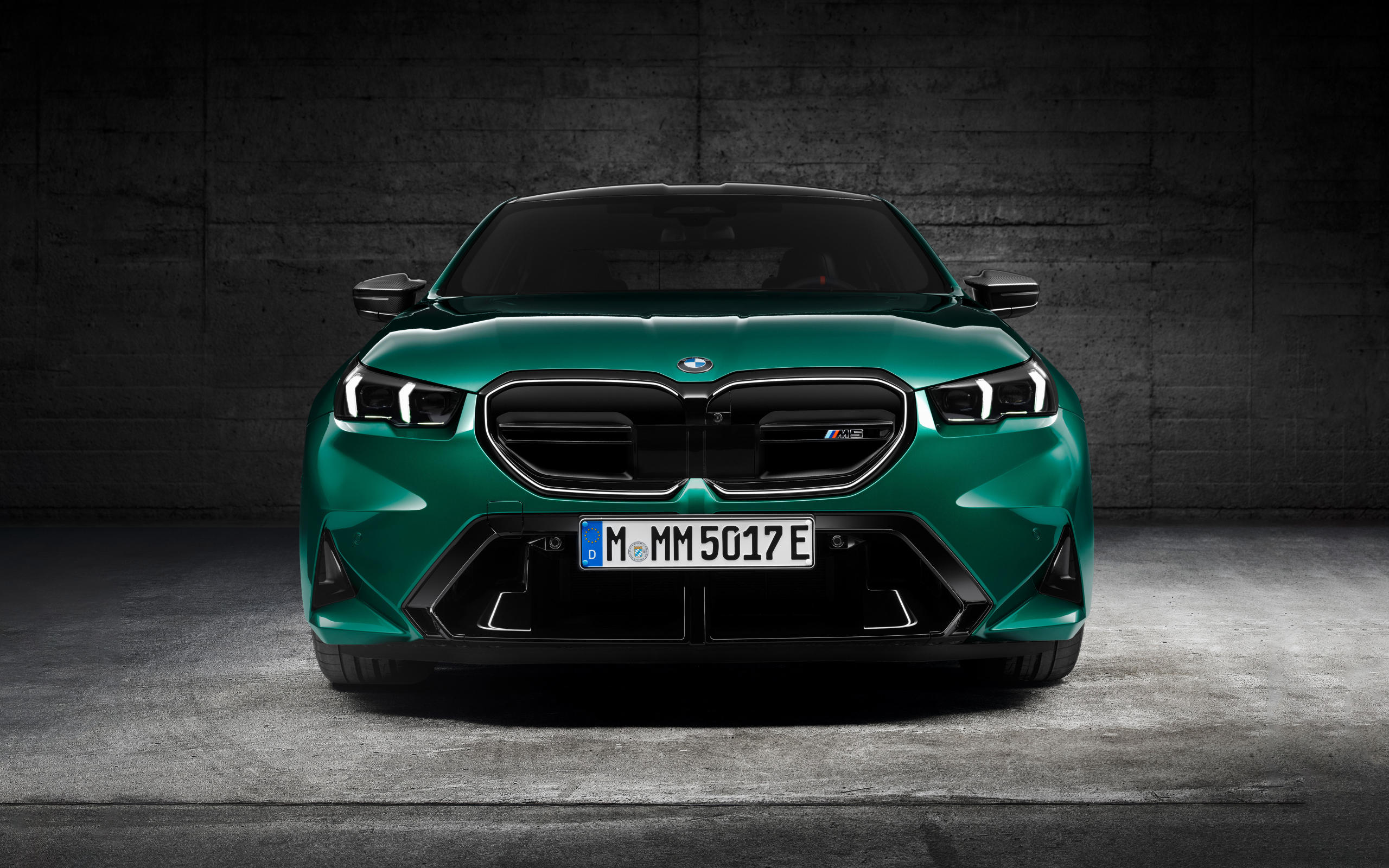 Зеленый автомобиль BMW M5 2024  года вид спереди