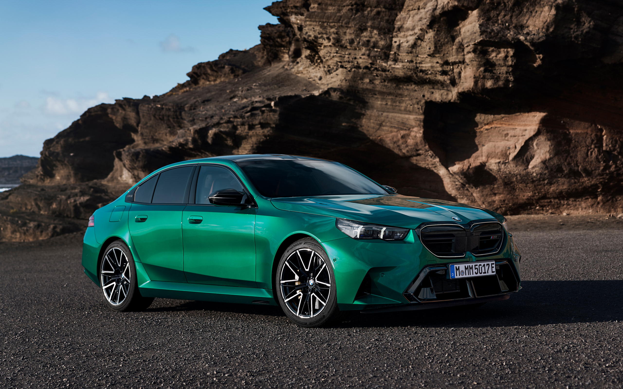 Зеленый автомобиль BMW M5 2024 года на фоне гор