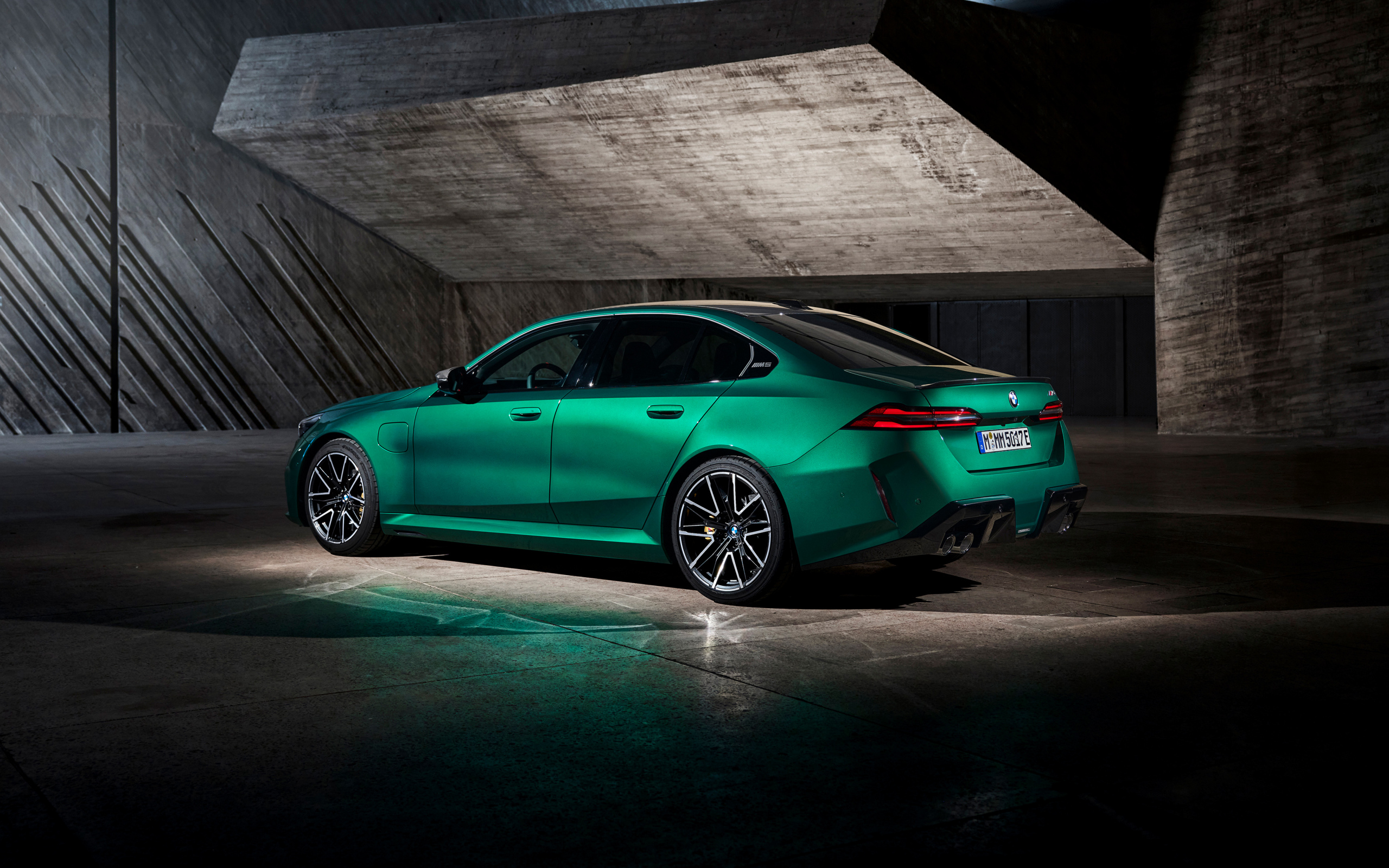 Вид сзади на зеленый автомобиль BMW M5 2024  года