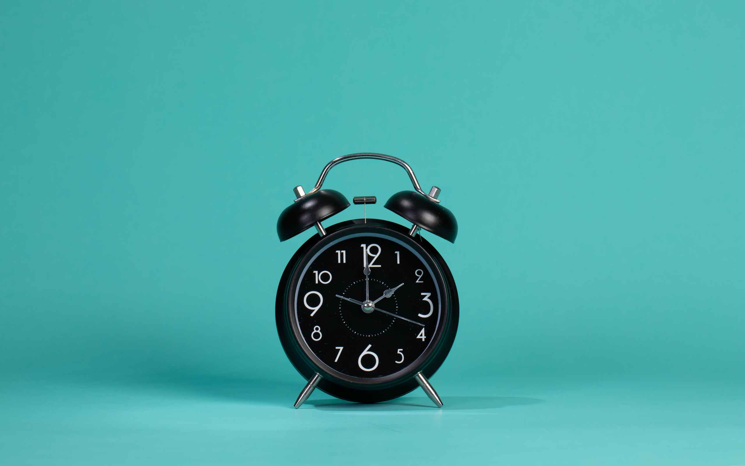Черный будильник на голубом фоне