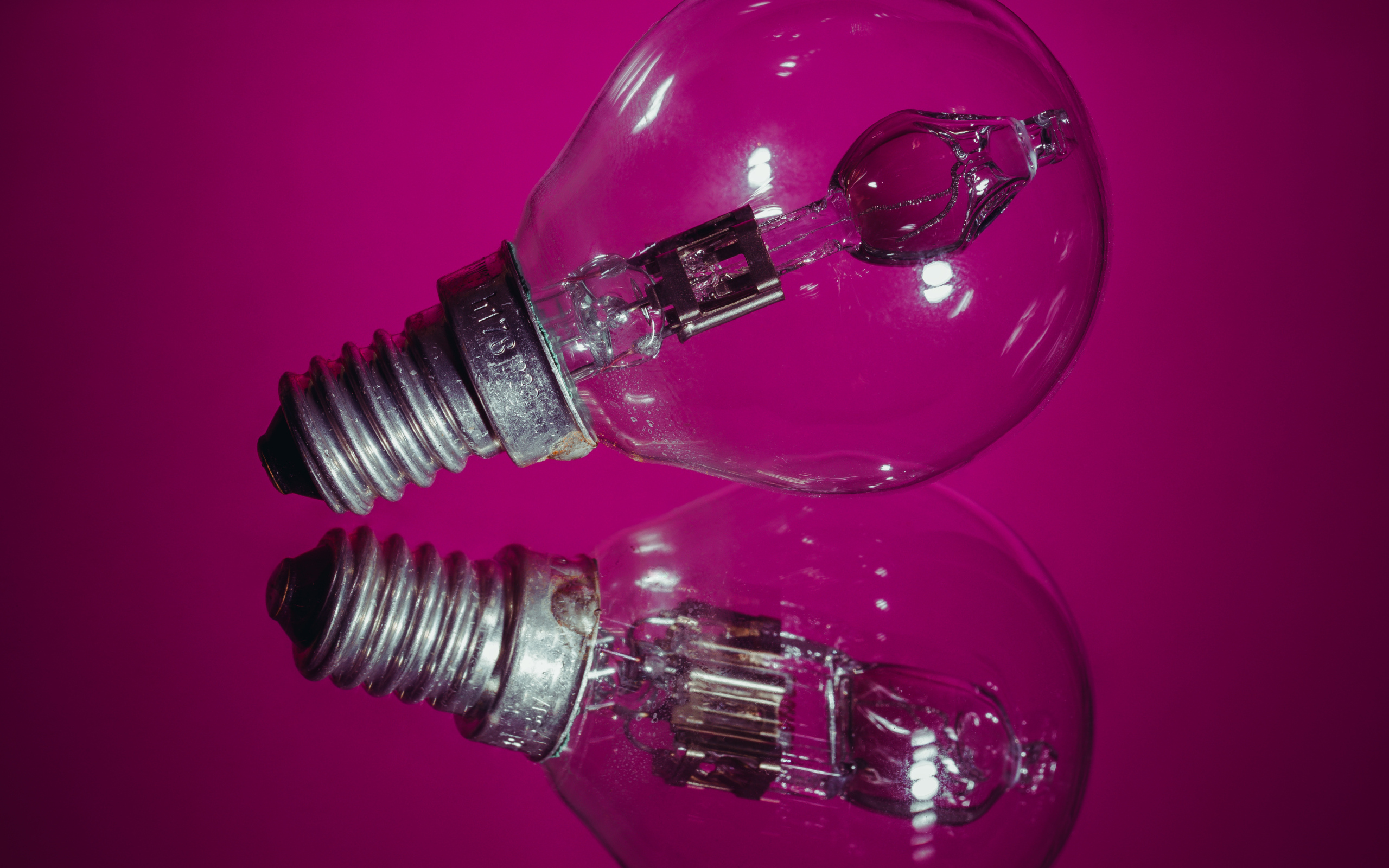 Лампочка отражается в поверхности на сиреневом фоне