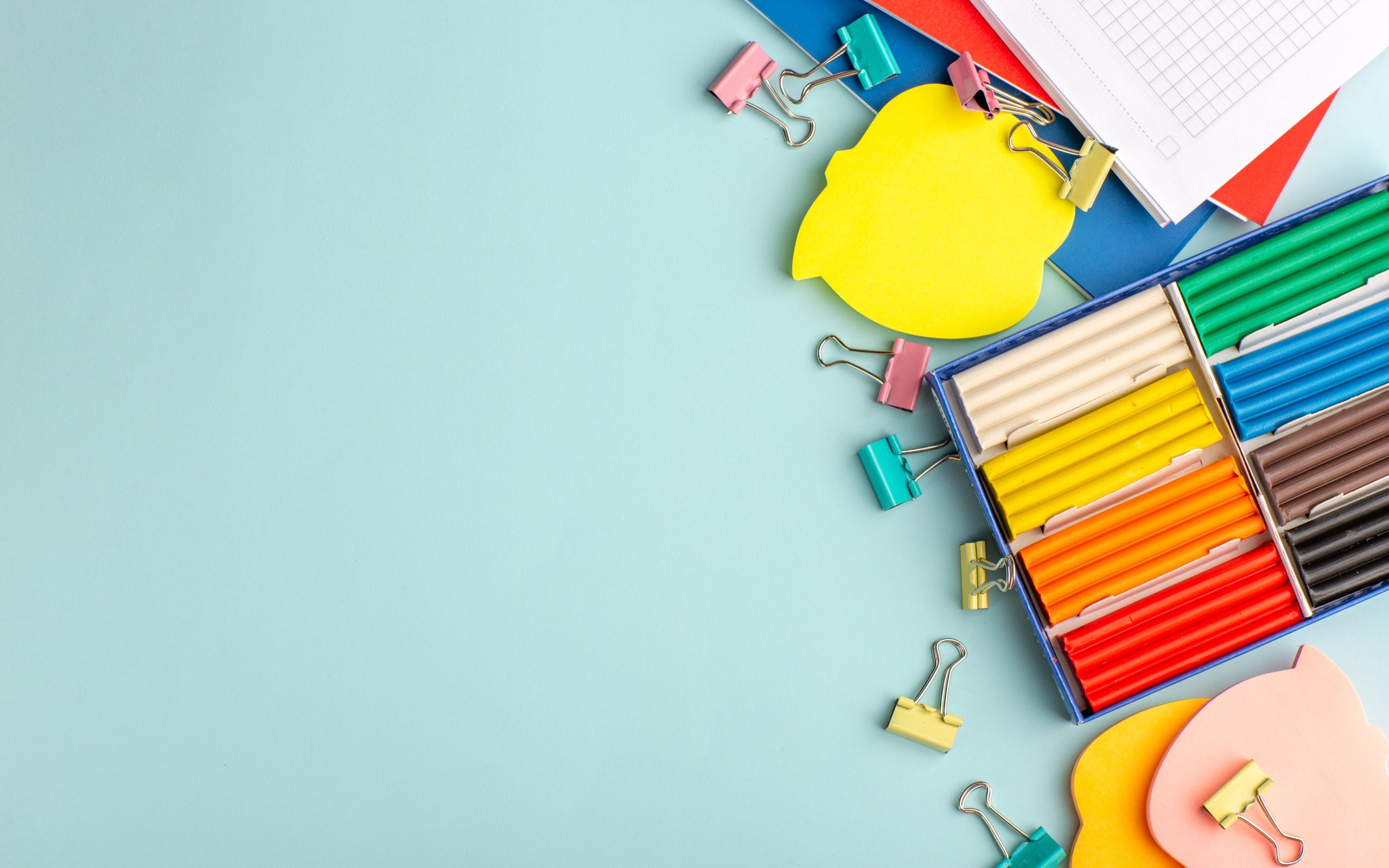 Пластилин на голубом фоне со скрепками и блокнотами