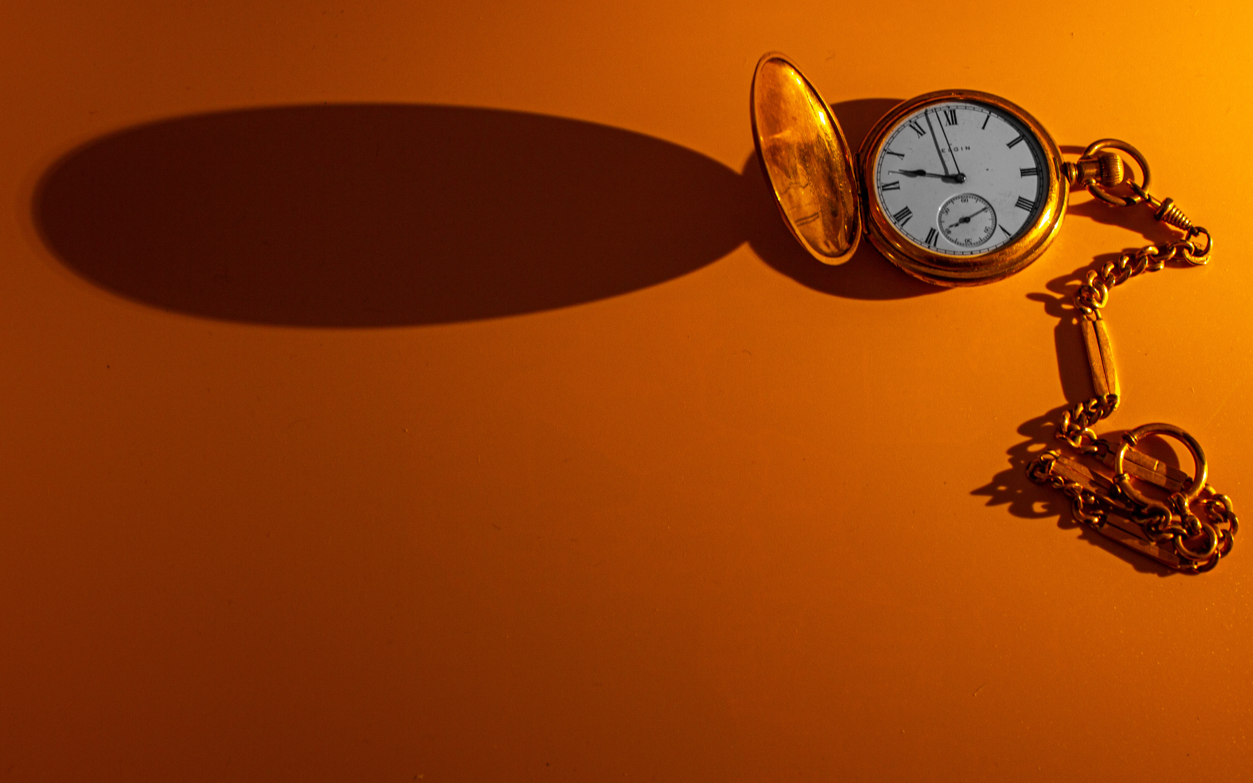 Тень от карманных часов на оранжевом фоне
