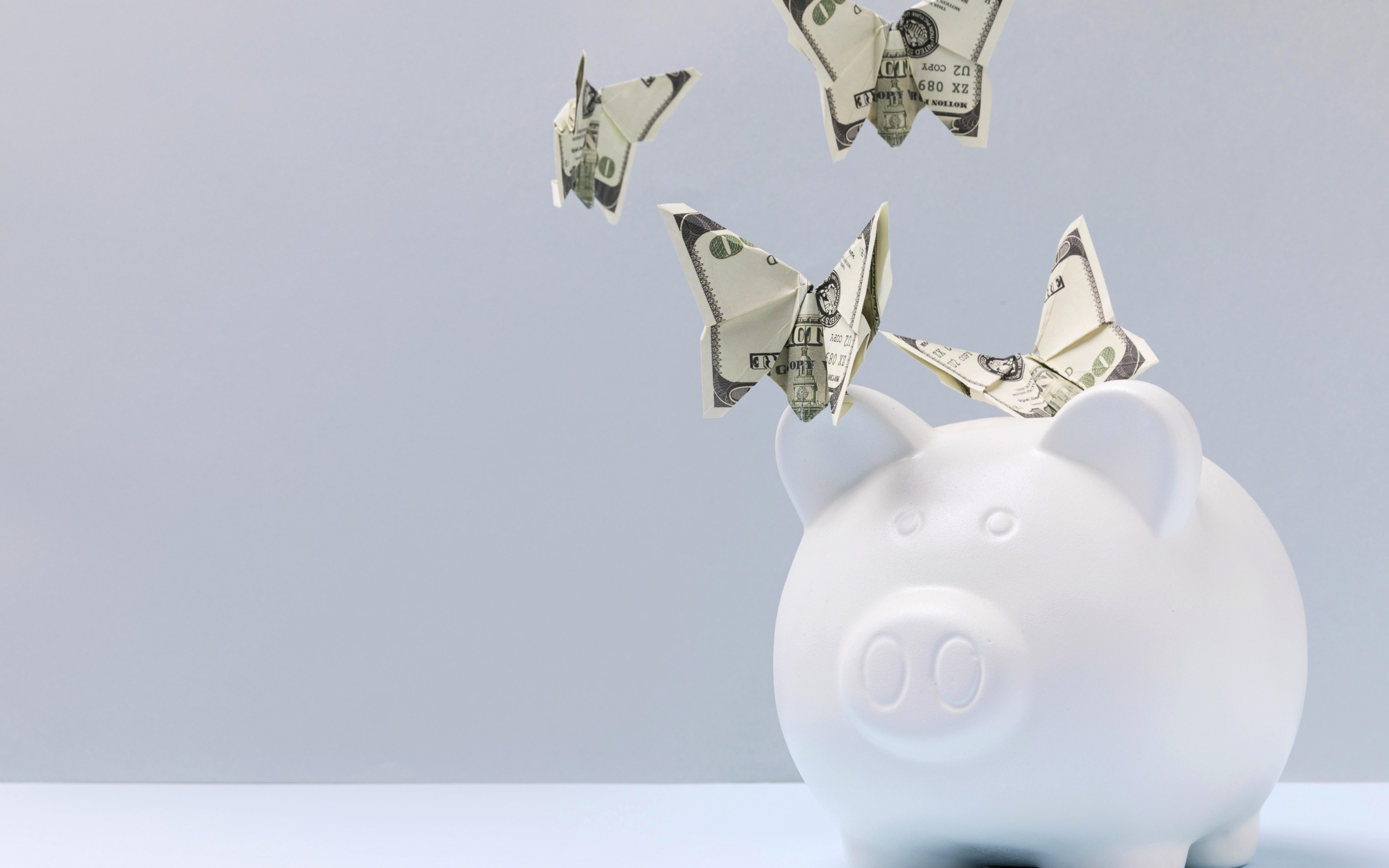 Свинья копилка с бабочками из купюр на сером фоне