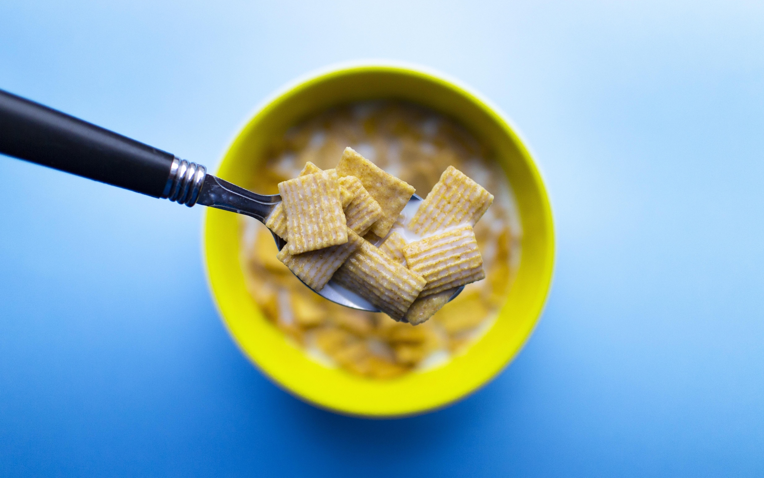 Хлопья с молоком на ложке на голубом фоне