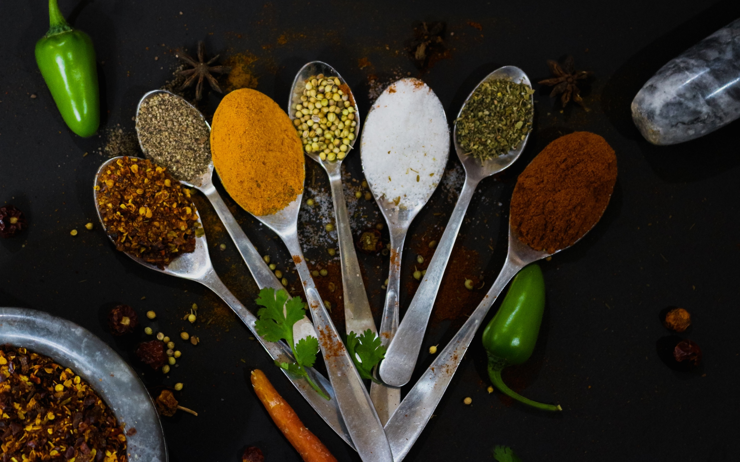 Ложки с ароматными специями на черном столе
