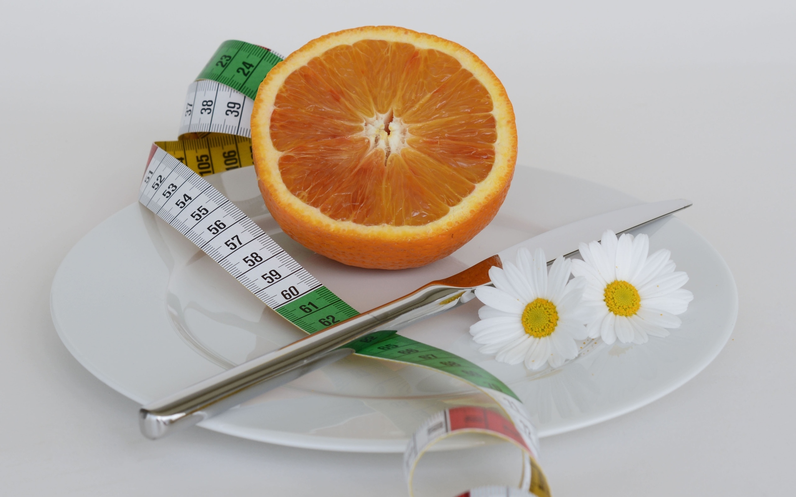 Половина апельсина на тарелке с сантиметром