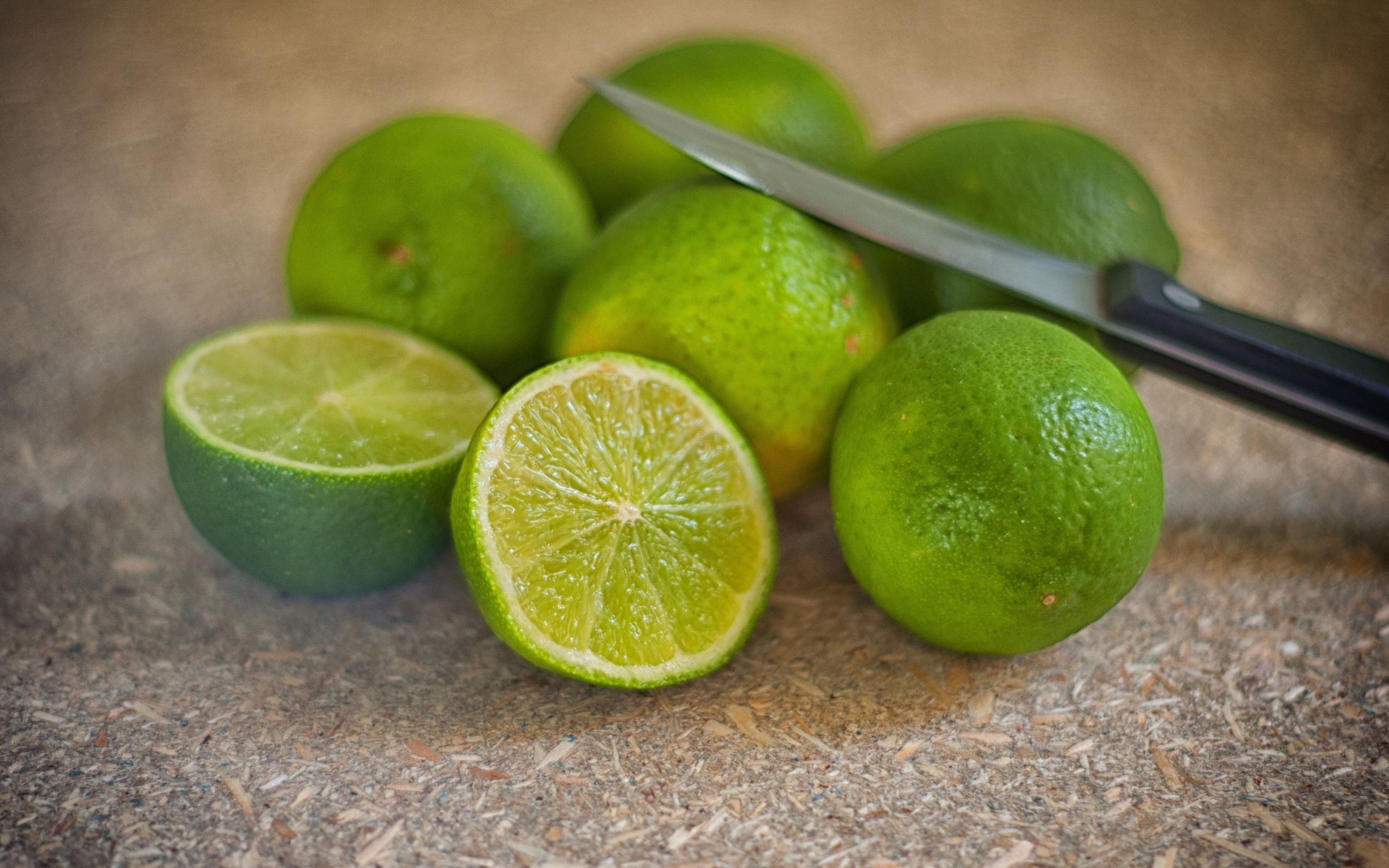 Много зеленых лаймов на столе с ножом