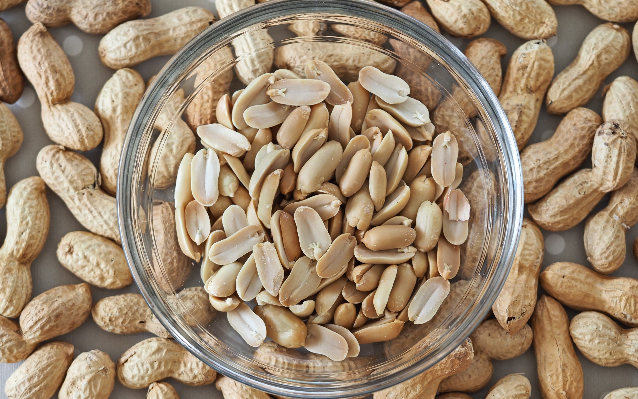 Арахис в стеклянной тарелке на столе 