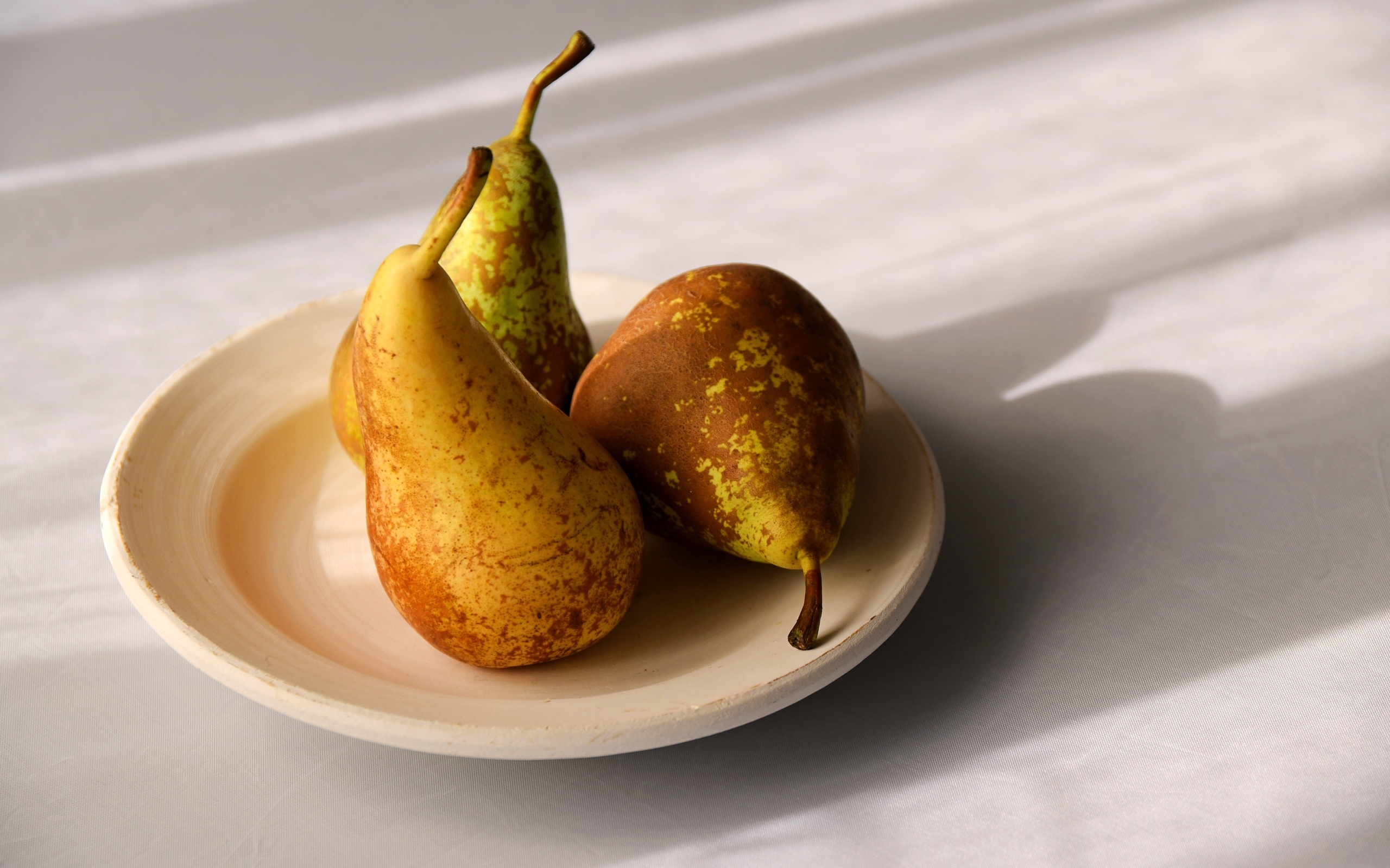 Три груши на тарелке на столе