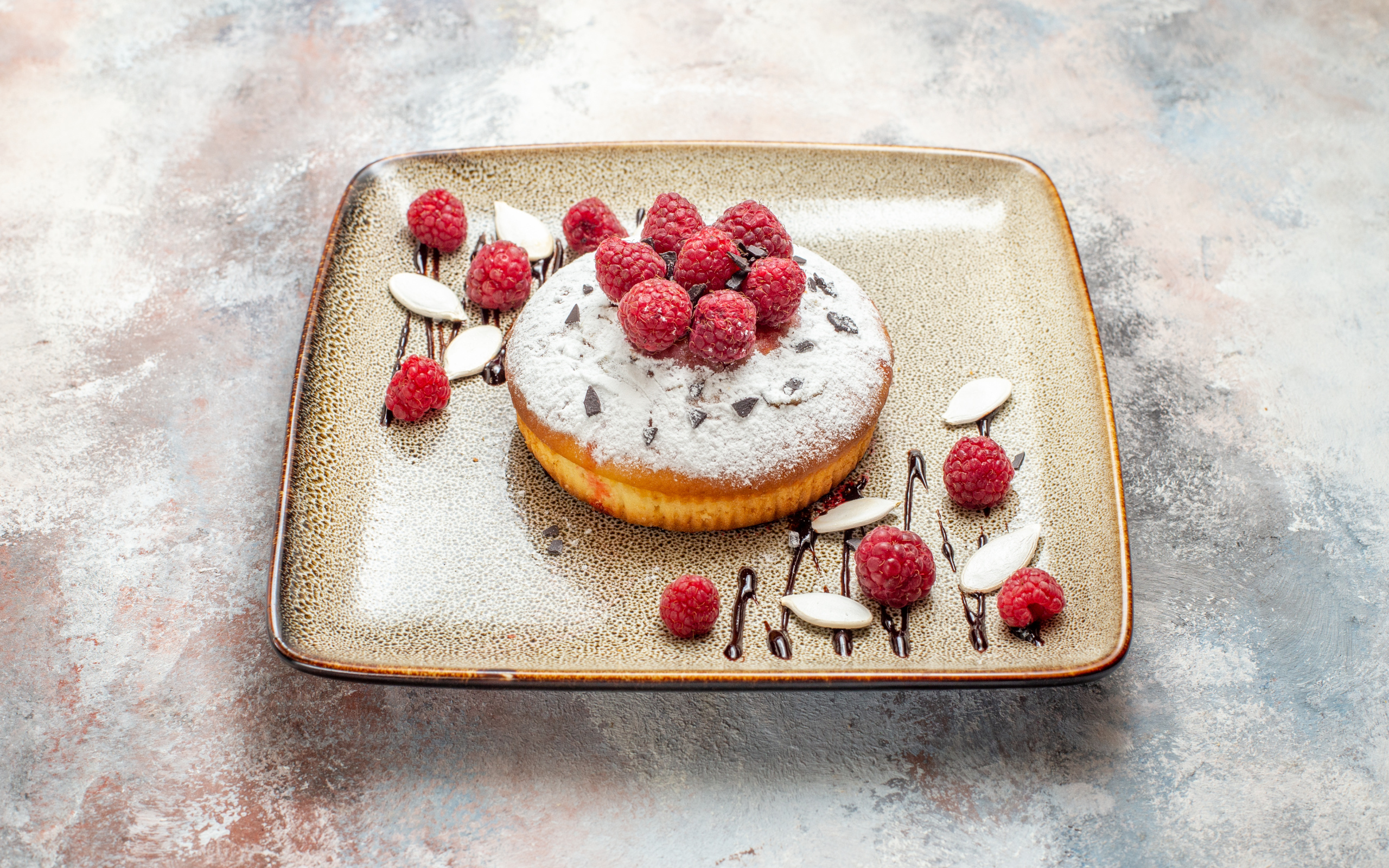 Пирожное с сахарной пудрой и малиной на тарелке