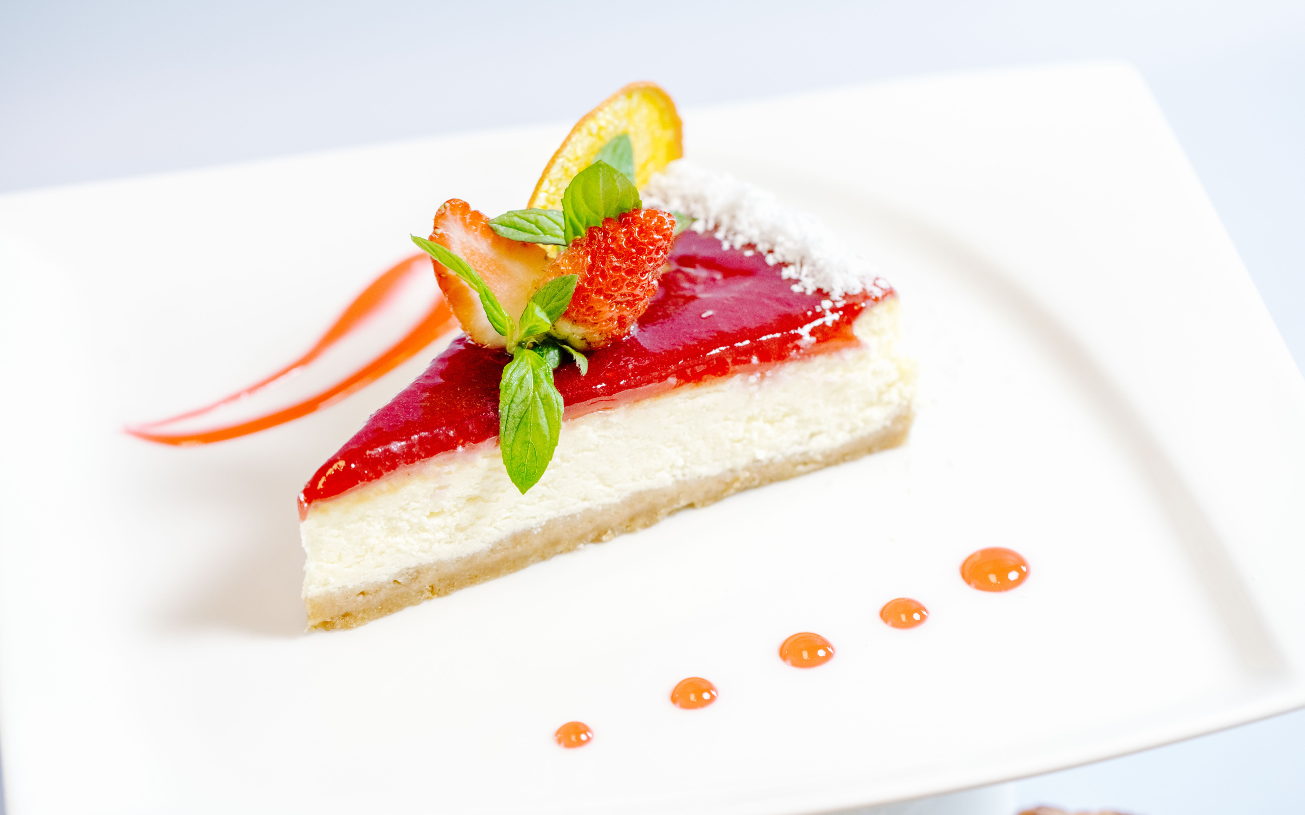 Чизкейк с клубничным джемом и ягодами на белой тарелке