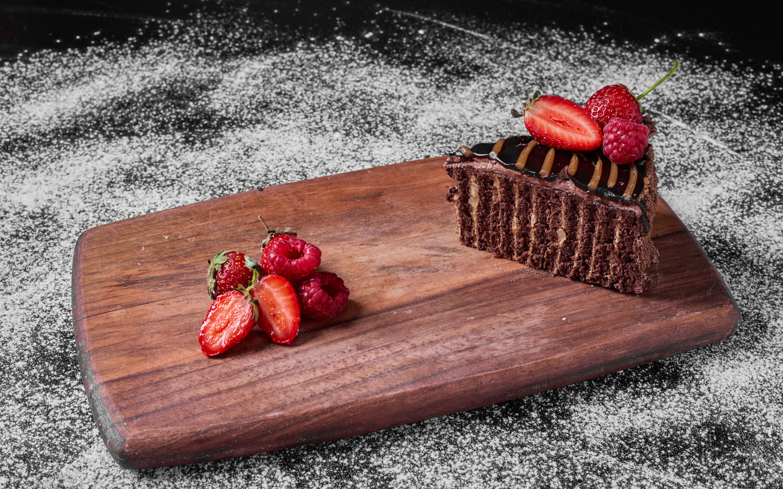 Кусок торта брауни с ягодами на доске