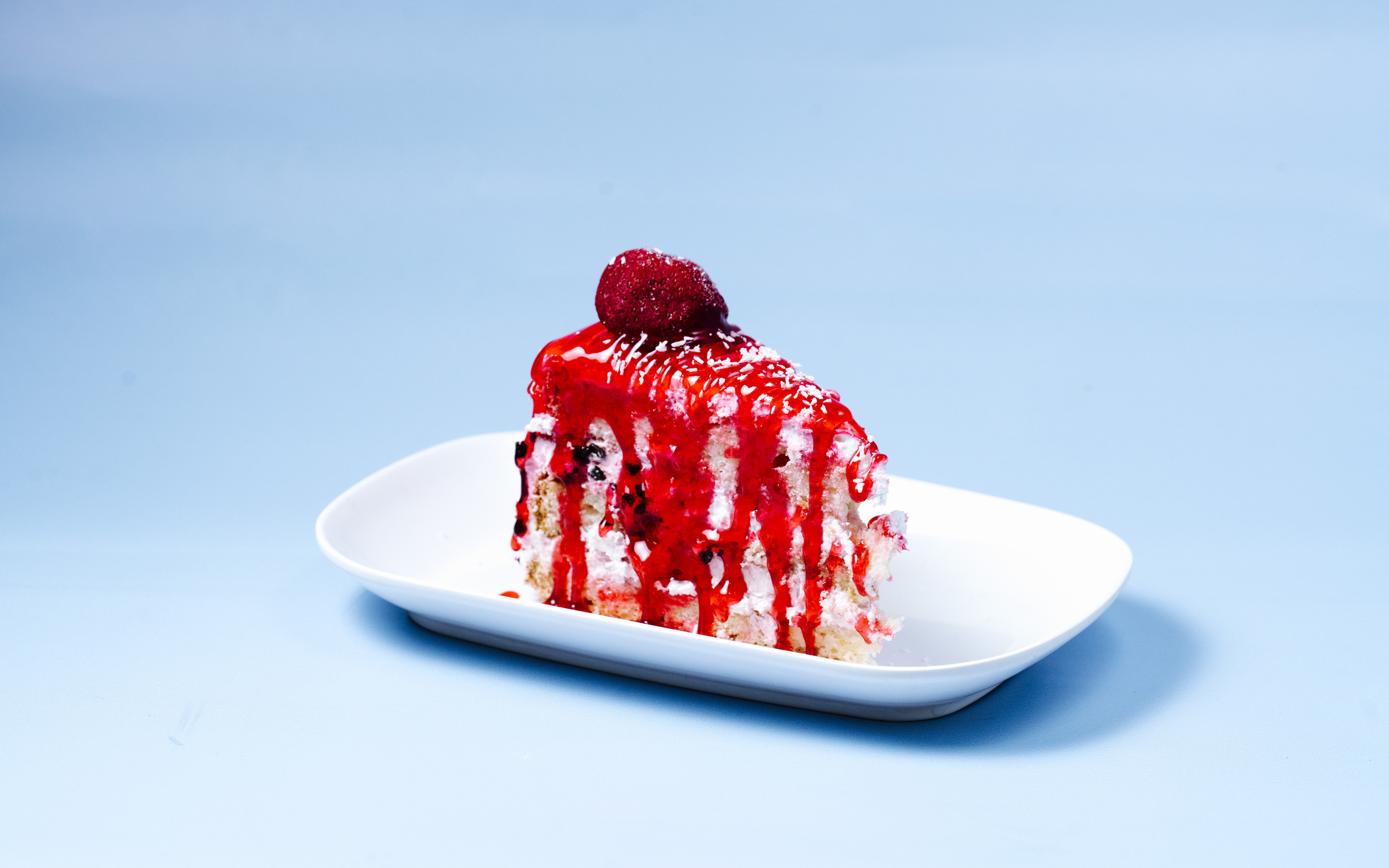 Кусок торта с клубничным сиропом на голубом фоне