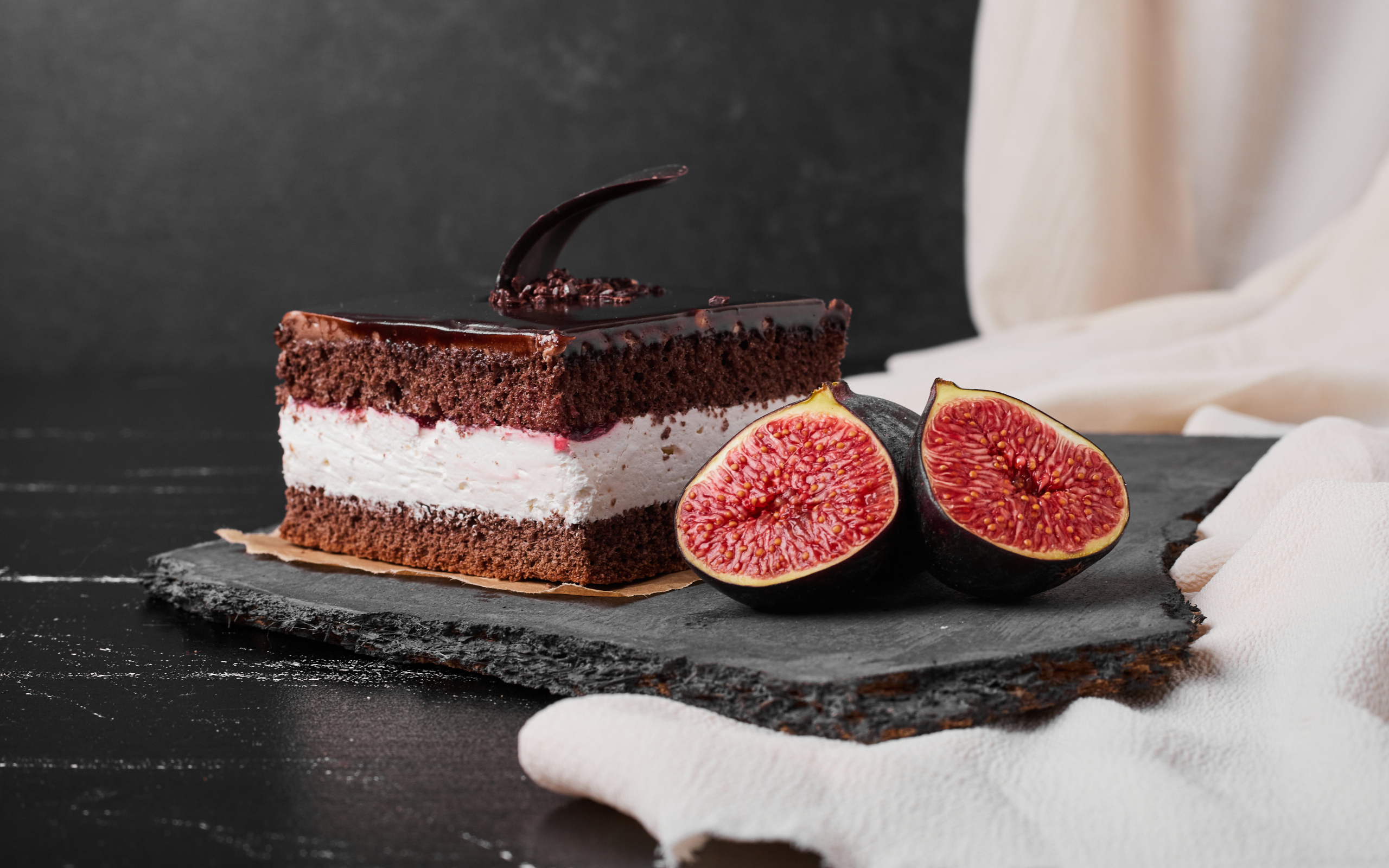 Кусок шоколадного торта с половинками инжира на столе