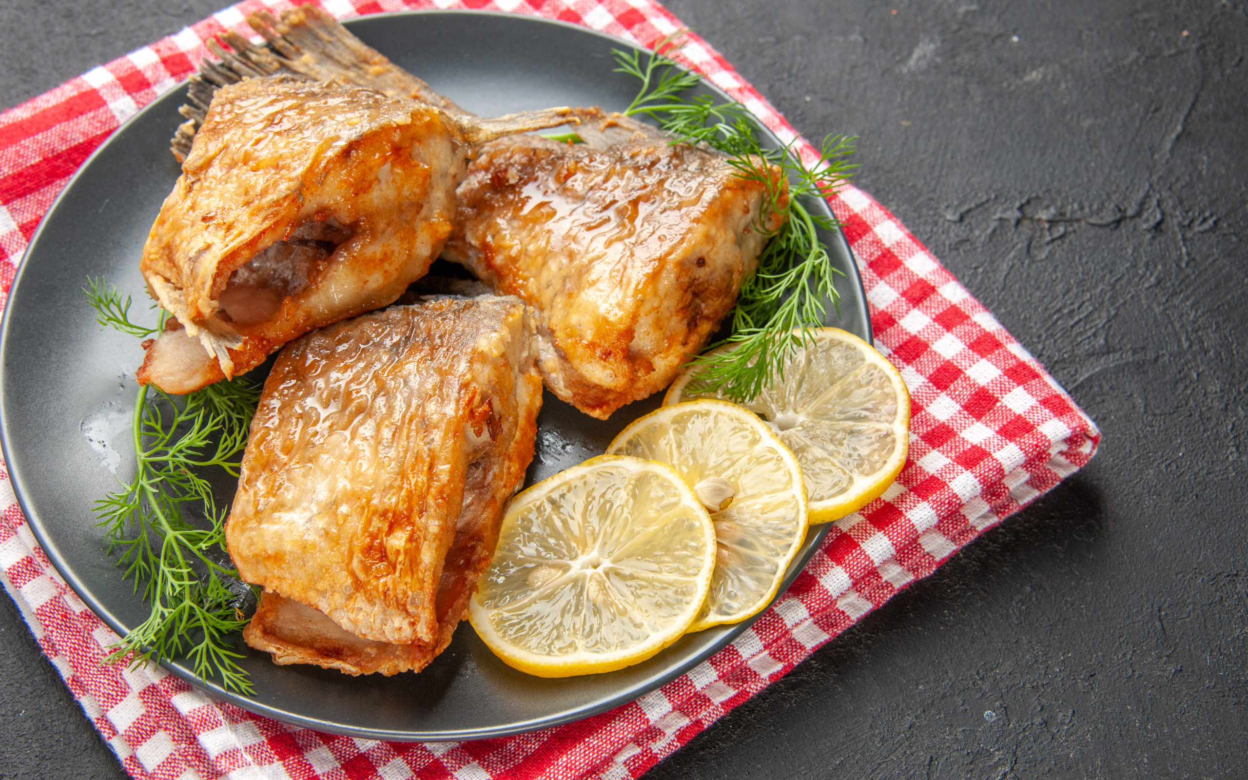 Куски жареной рыбы на тарелке с кусочками лимона и укропом