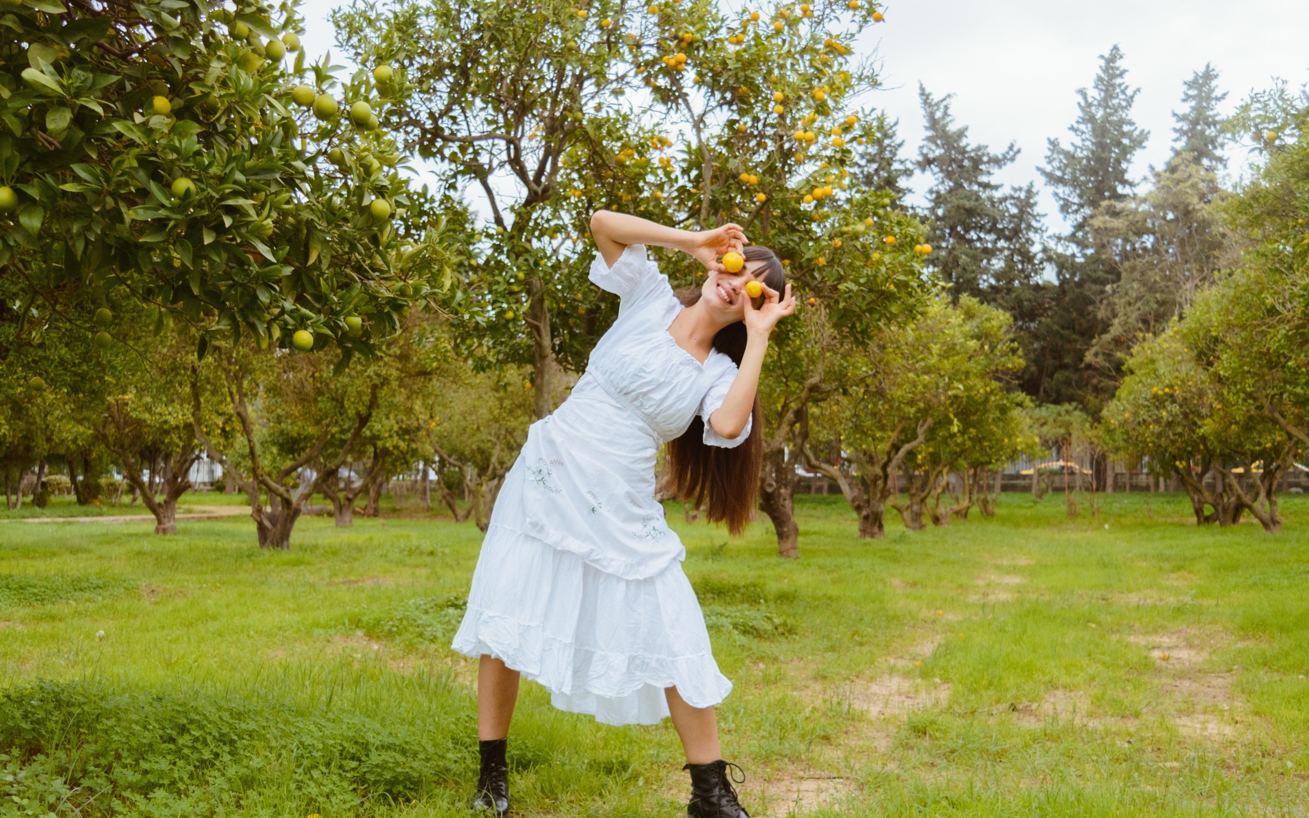 Девушка в белом платье закрыла глаза лимонами