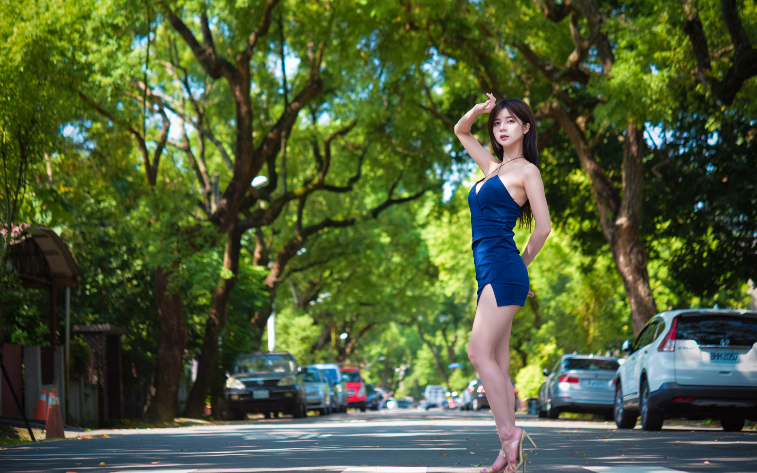Стройная азиатка в коротком платье стоит на дороге