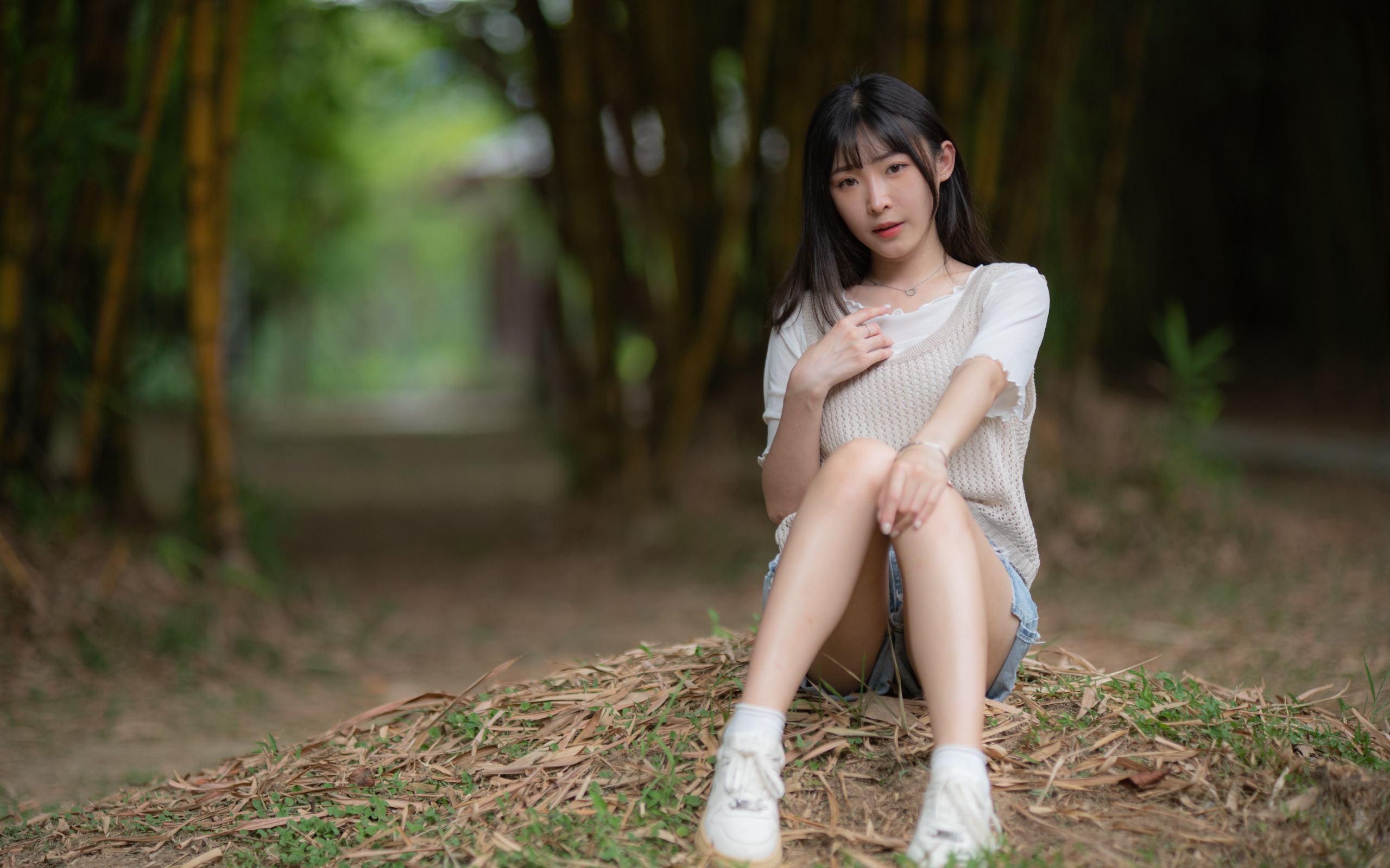 Азиатка сидит на земле в парке