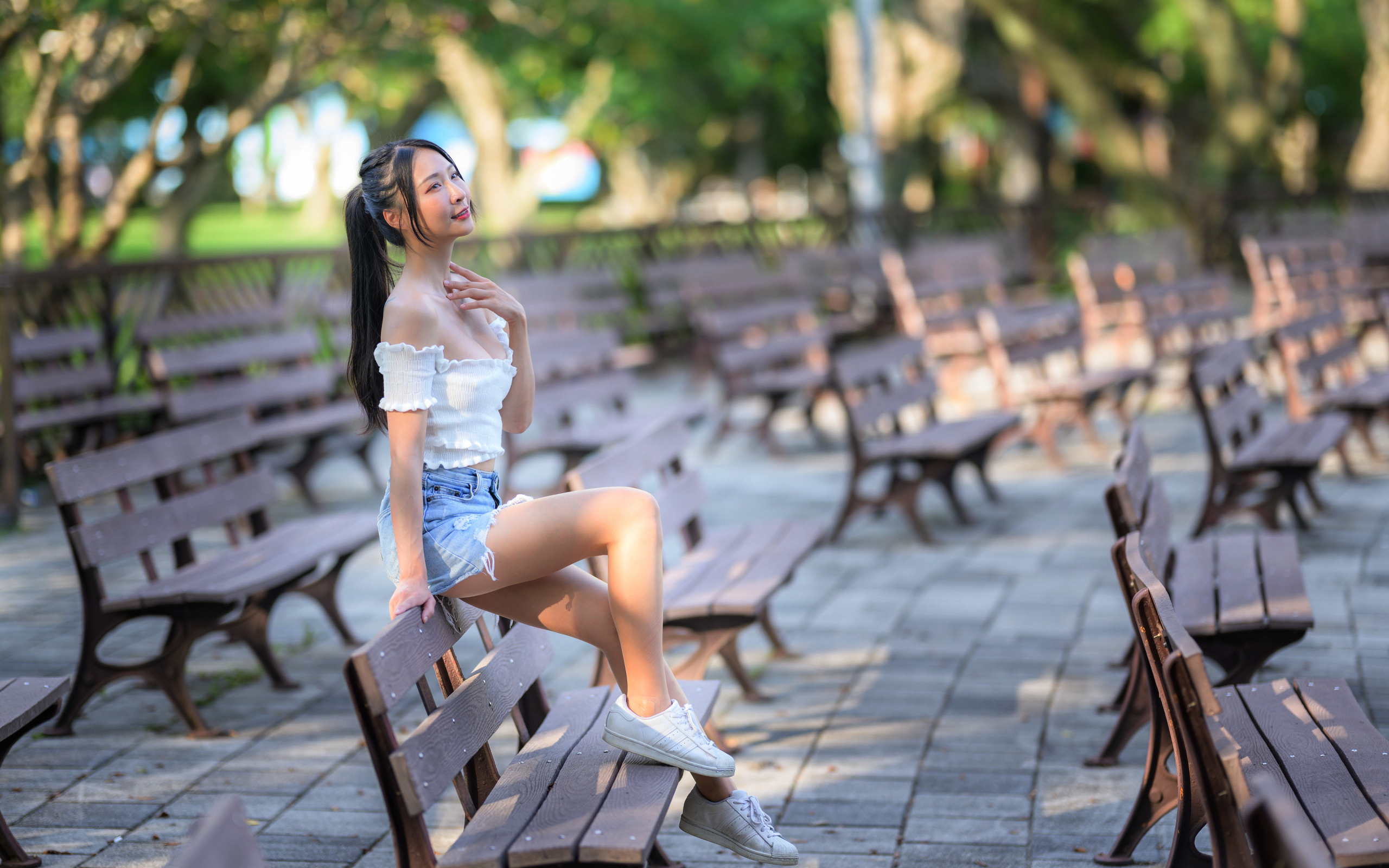 Спортивная азиатка сидит на лавке в парке