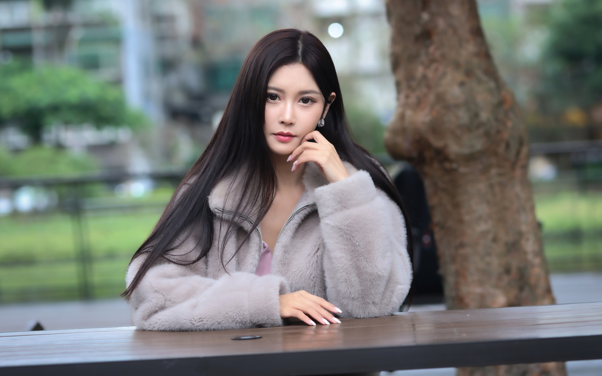 Кареглазая азиатка сидит в парке за столом