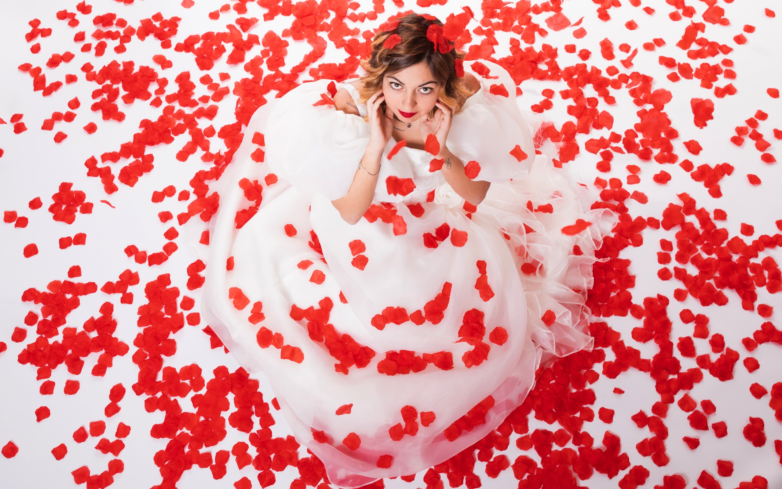 Девушка в белом платье сидит на лепестках розы