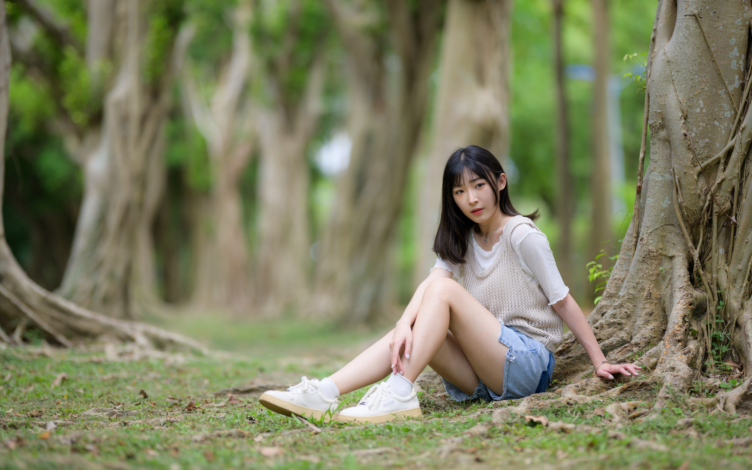 Молодая девушка азиатка сидит у дерева в парке