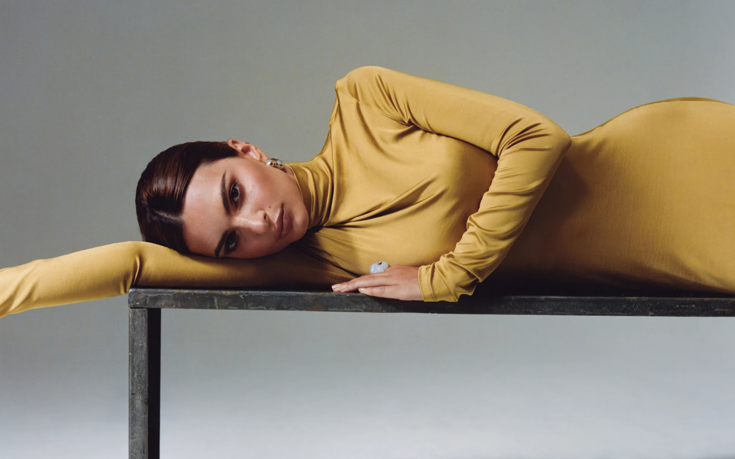 Красивая модель Эмили Ратаковски в желтом платье лежит на столе