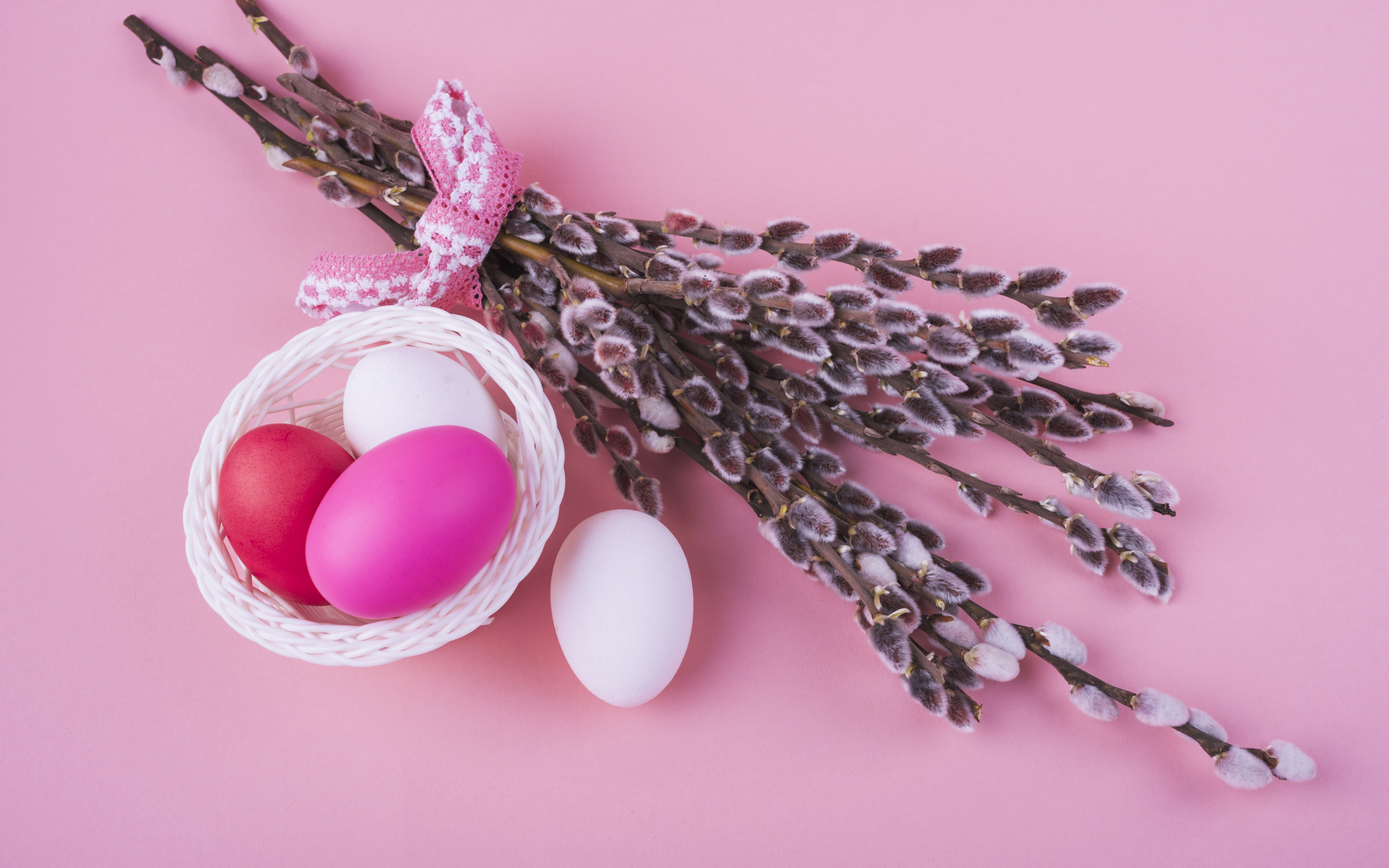 Ветки вербы с яйцами на розовом фоне