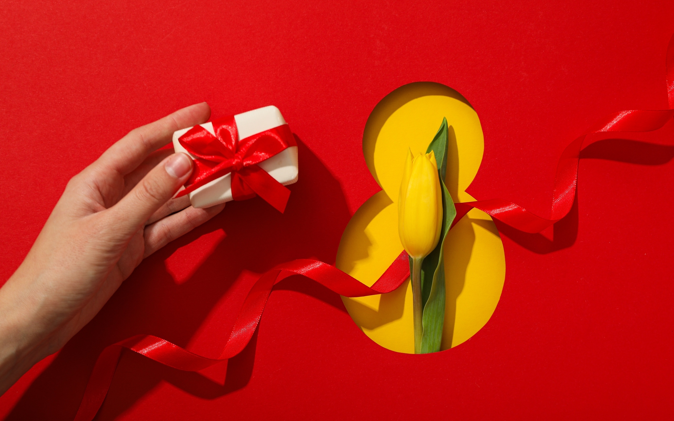 Красный фон с подарком, желтым тюльпаном и цифрой на 8 марта