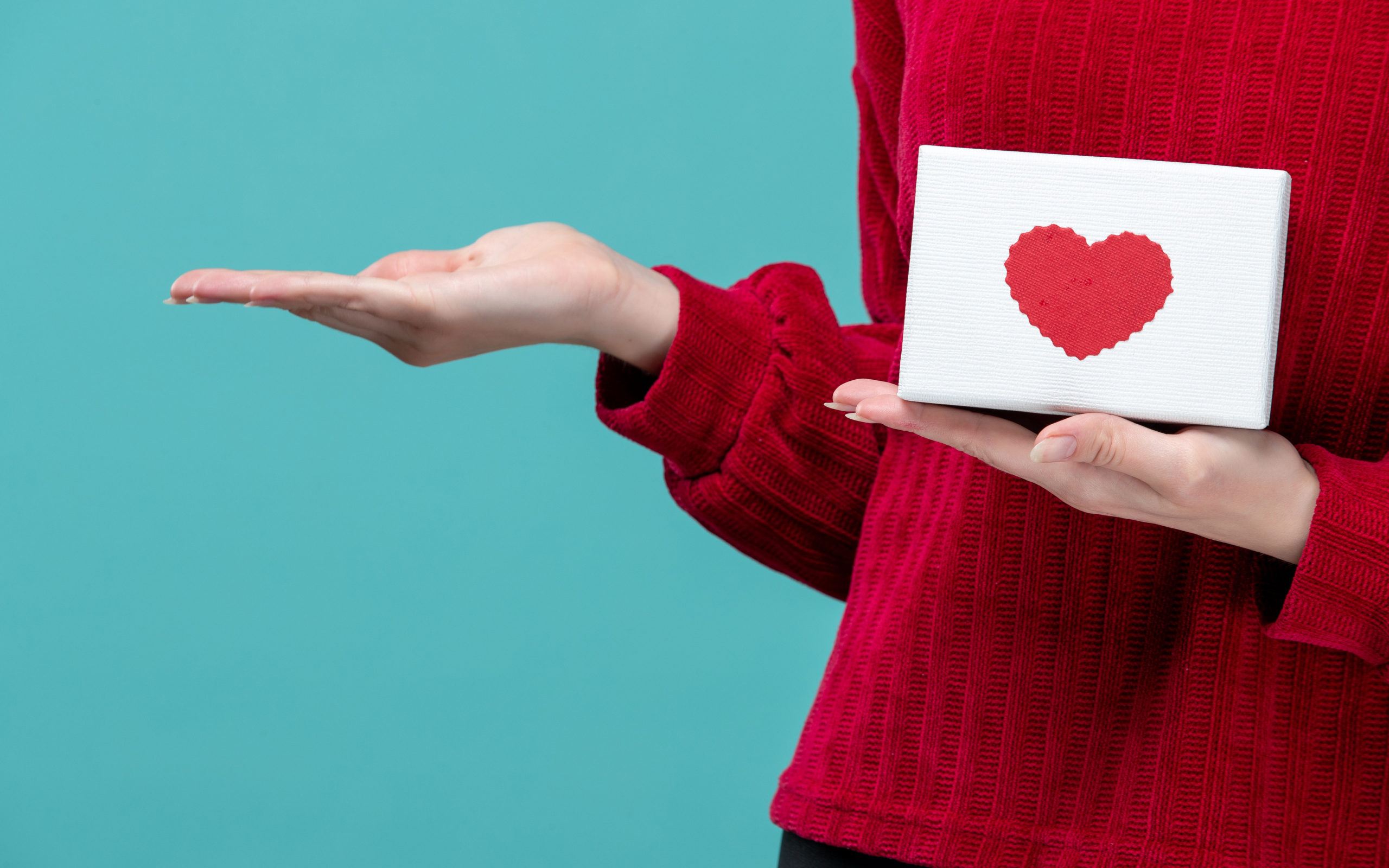 Коробка с сердцем в руке у девушки на голубом фоне