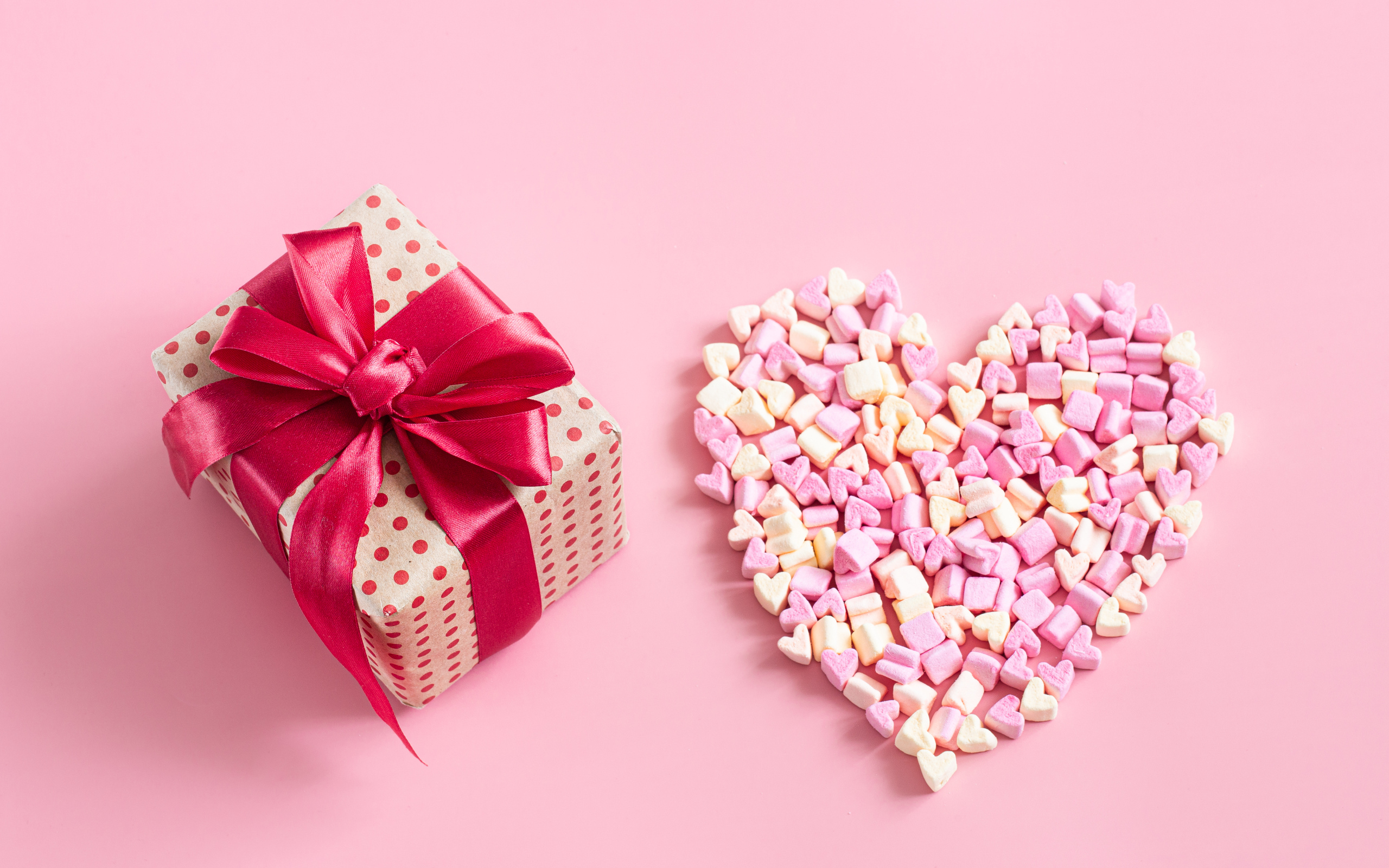 Подарок и сердце из конфет на розовом фоне