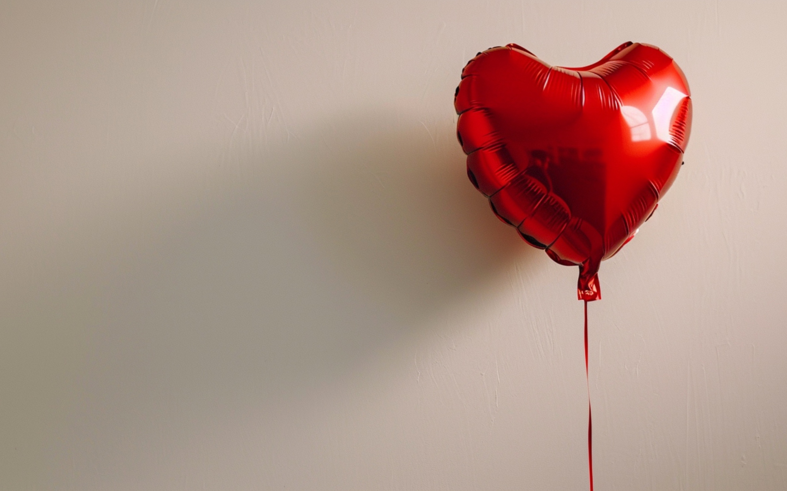 Красный шарик в форме сердца на сером фоне