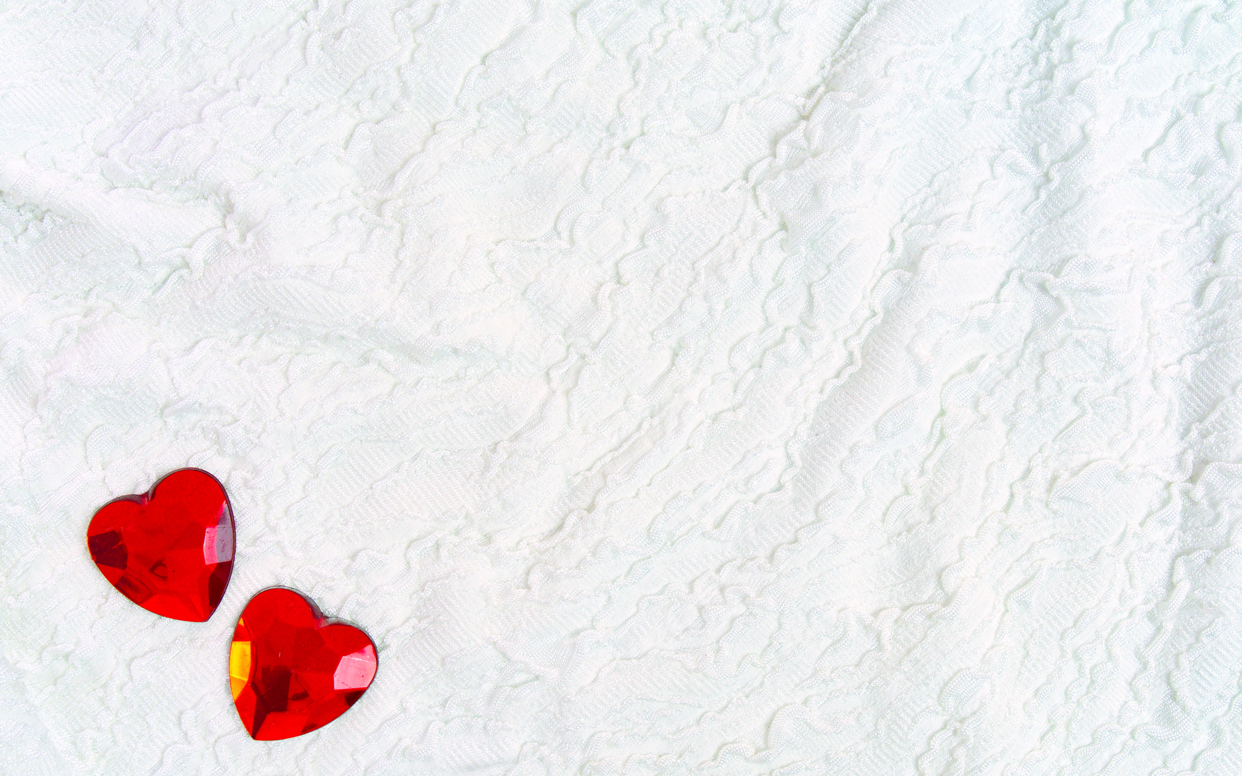 Два красных сердца из пластика на белой ткани