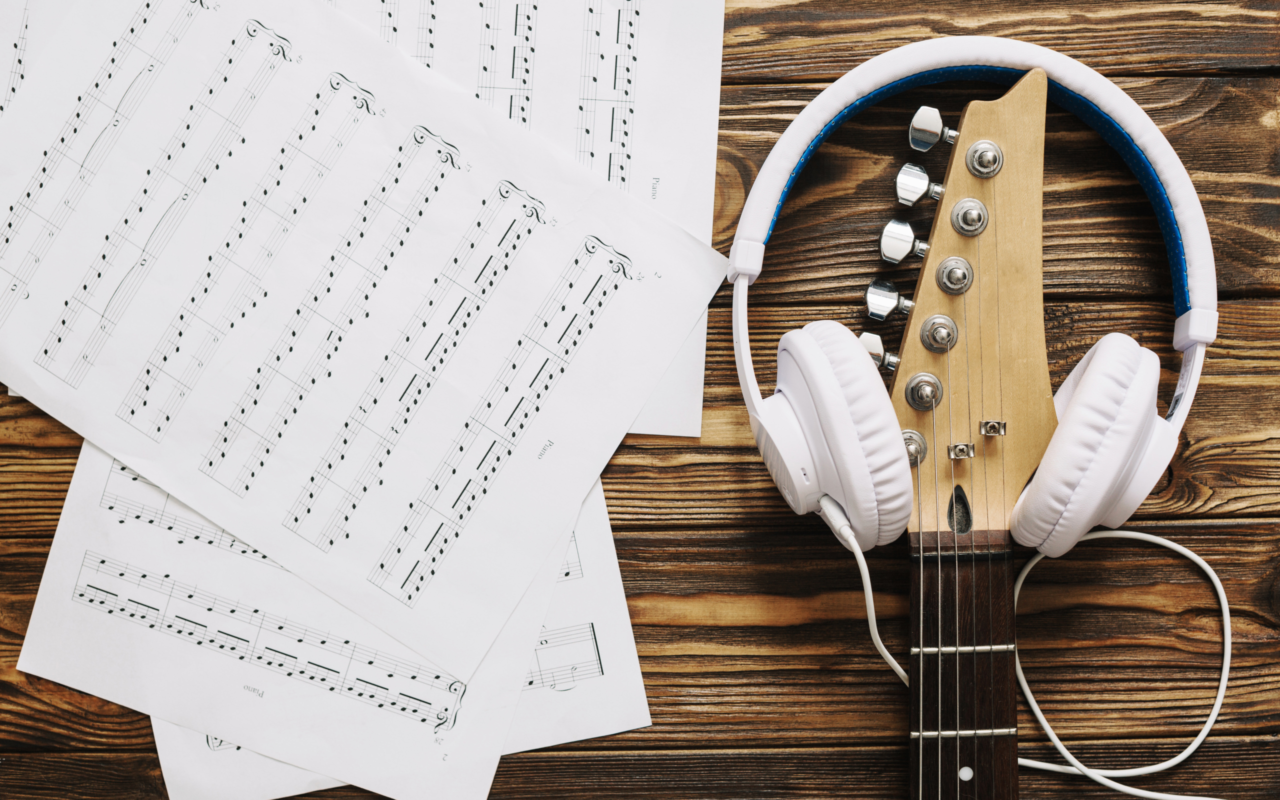 Ноты, наушники и гитара на столе