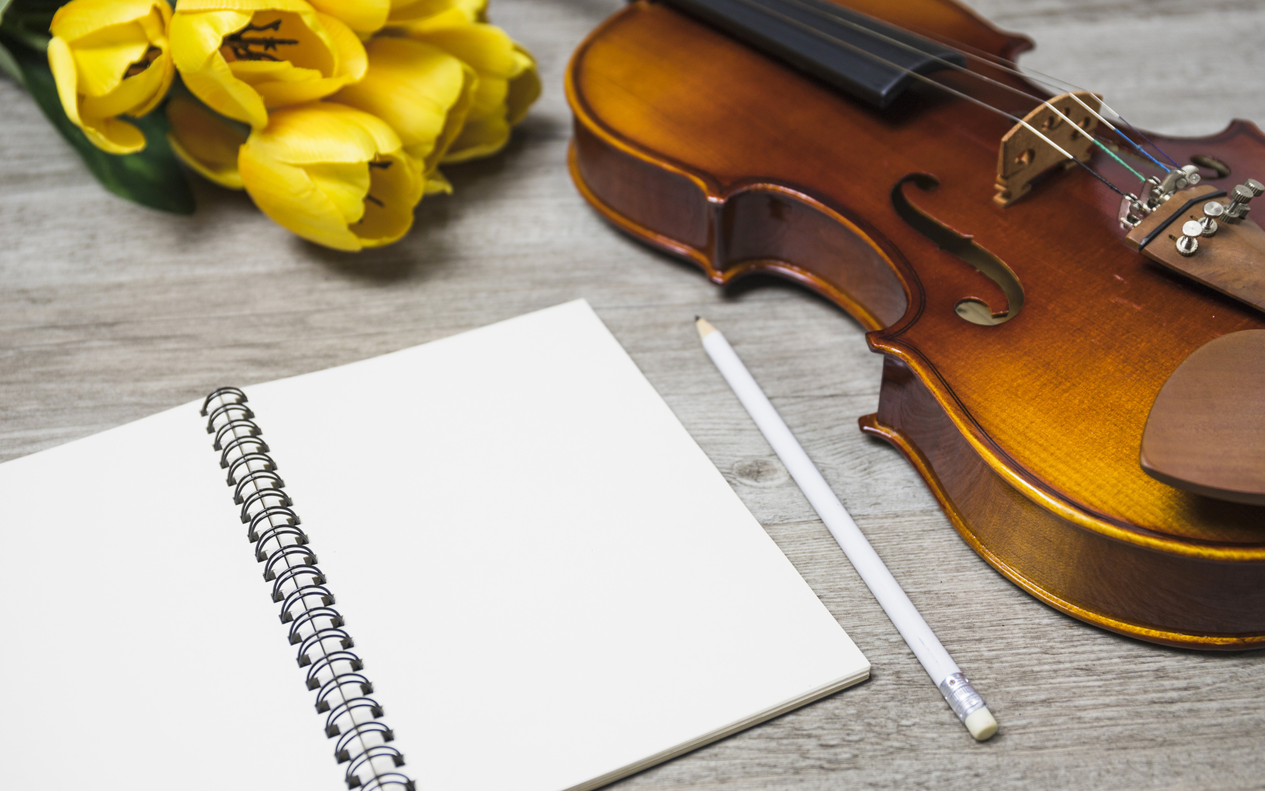 Скрипка, блокнот и желтые тюльпаны на столе