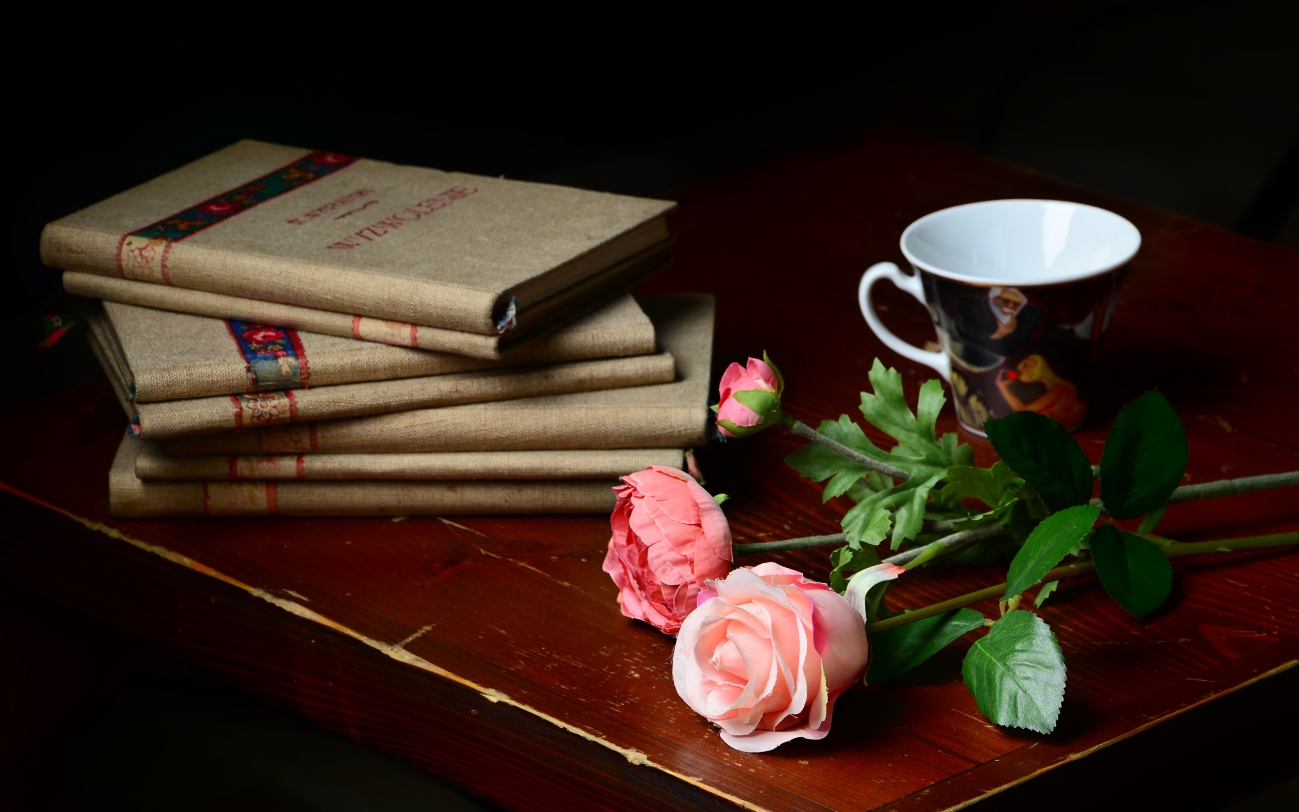 Книги на столе с цветами и чашкой