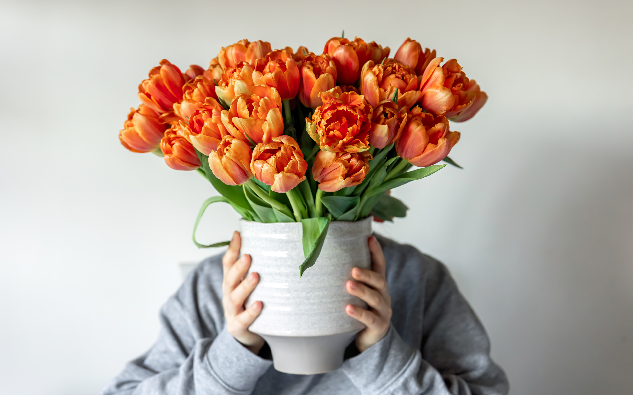 Букет оранжевых тюльпанов в вазе в руках