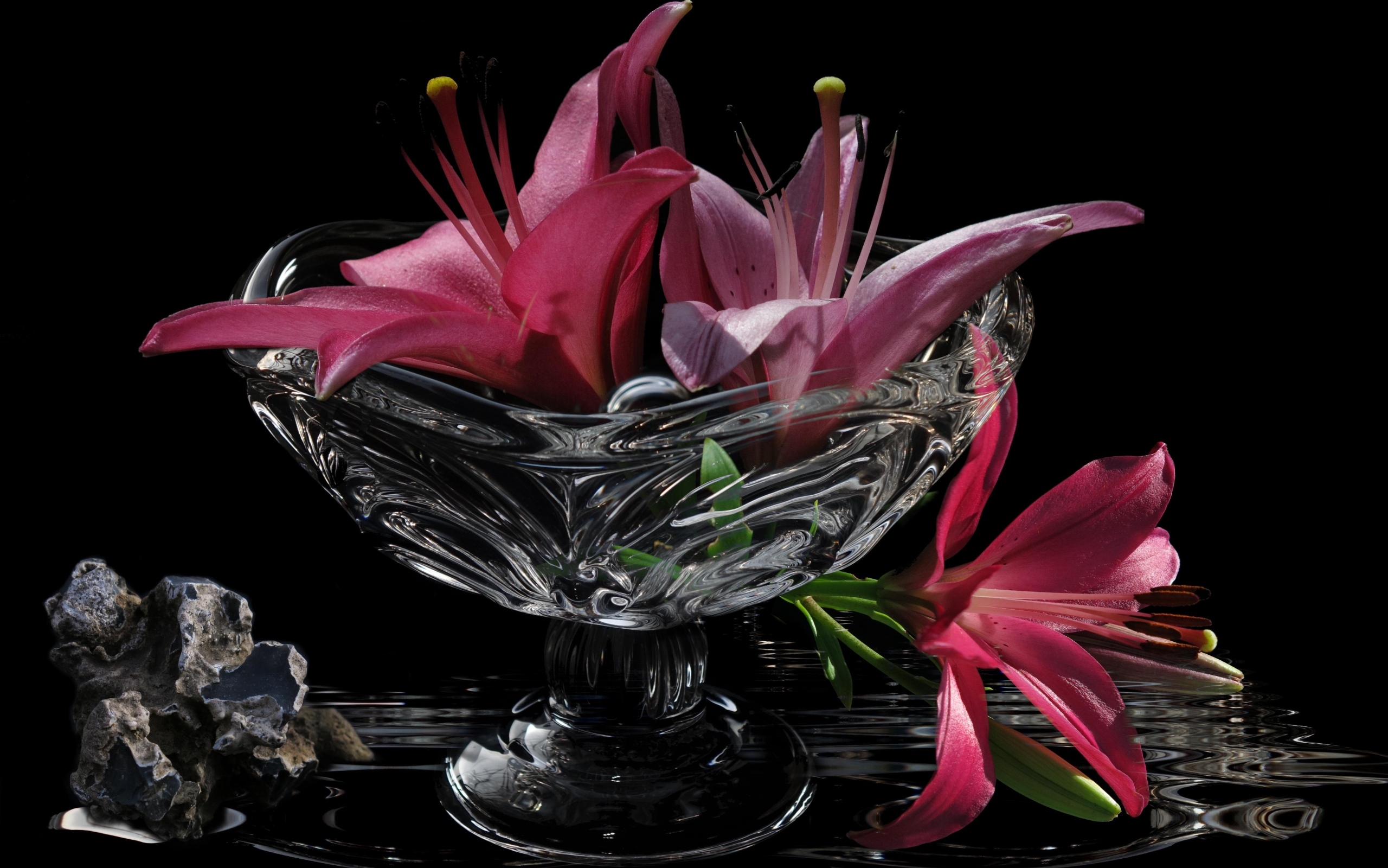 Розовые лилии в стеклянной вазе на столе