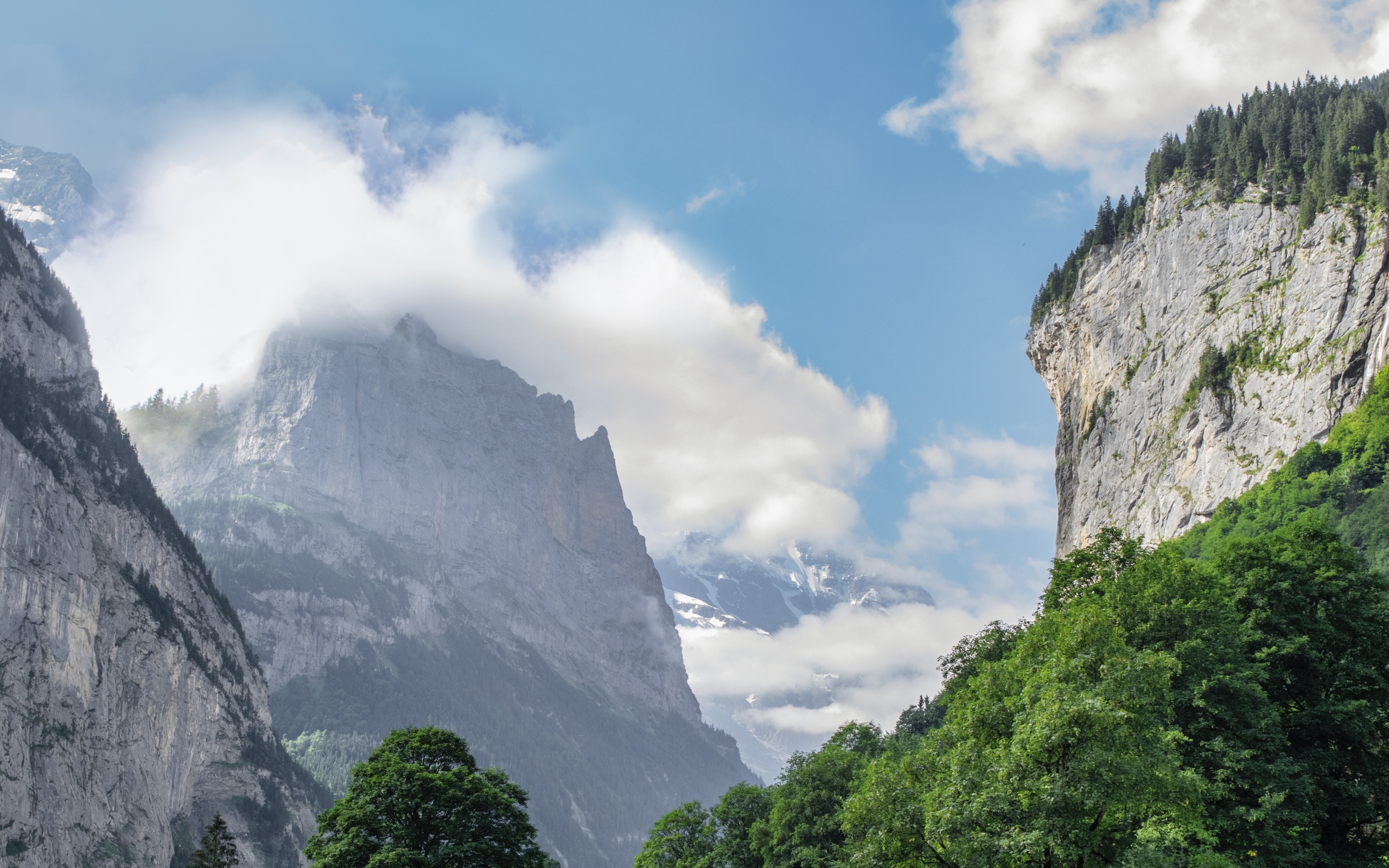 Высокие покрытые зеленью горы в белых облаках