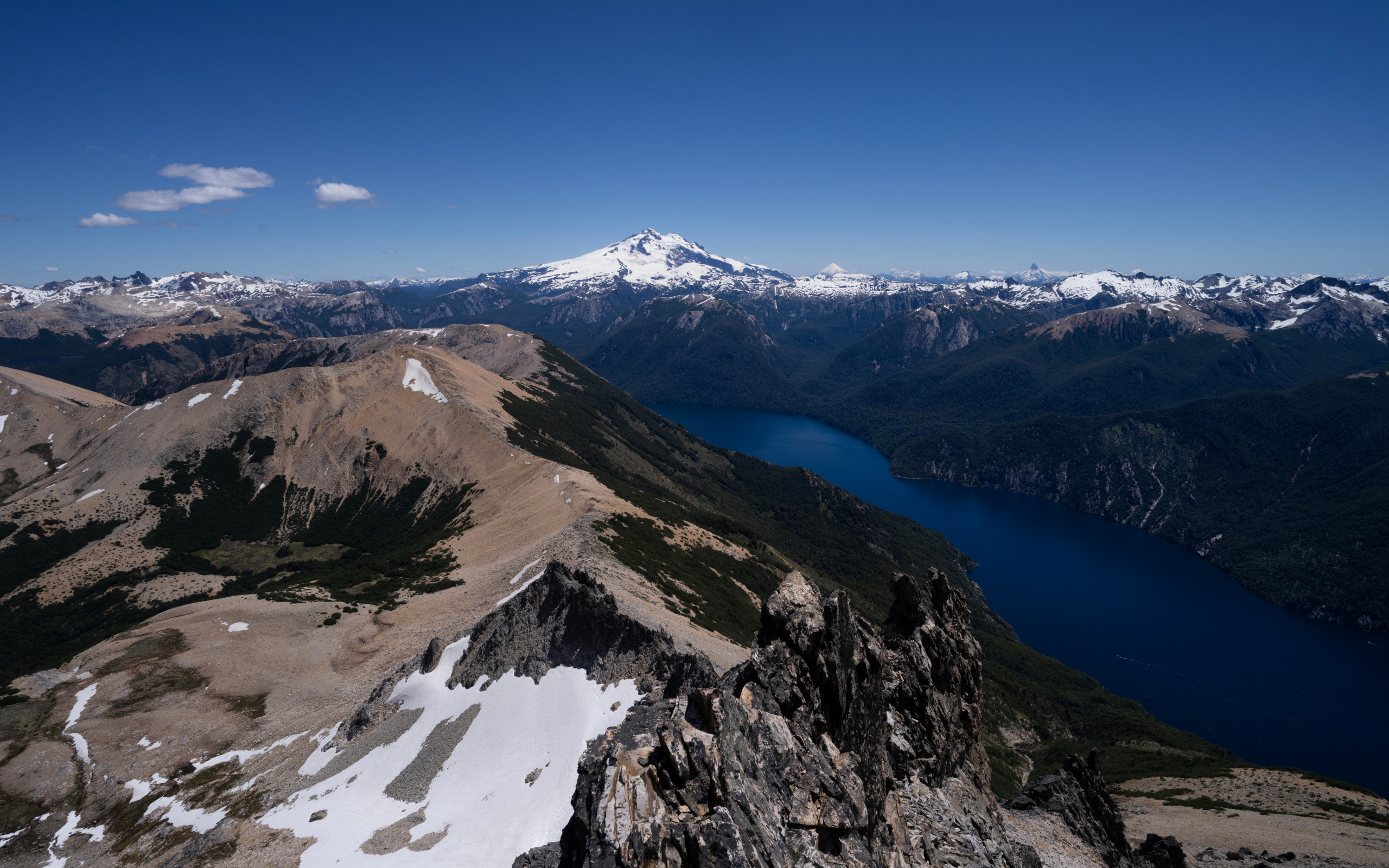 Высокие заснеженные горы и река под голубым небом