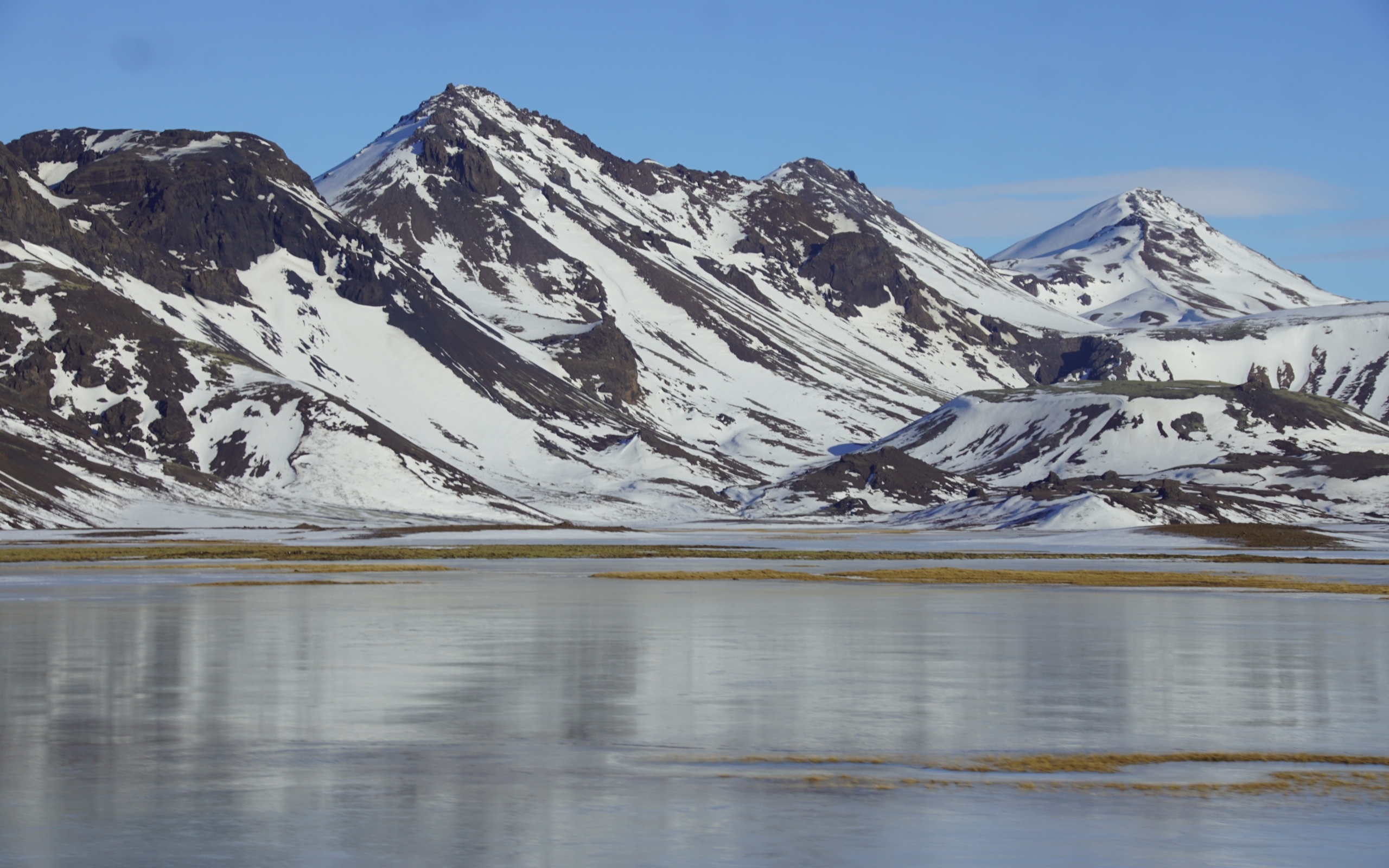 Горы в снегу под голубым небом у воды