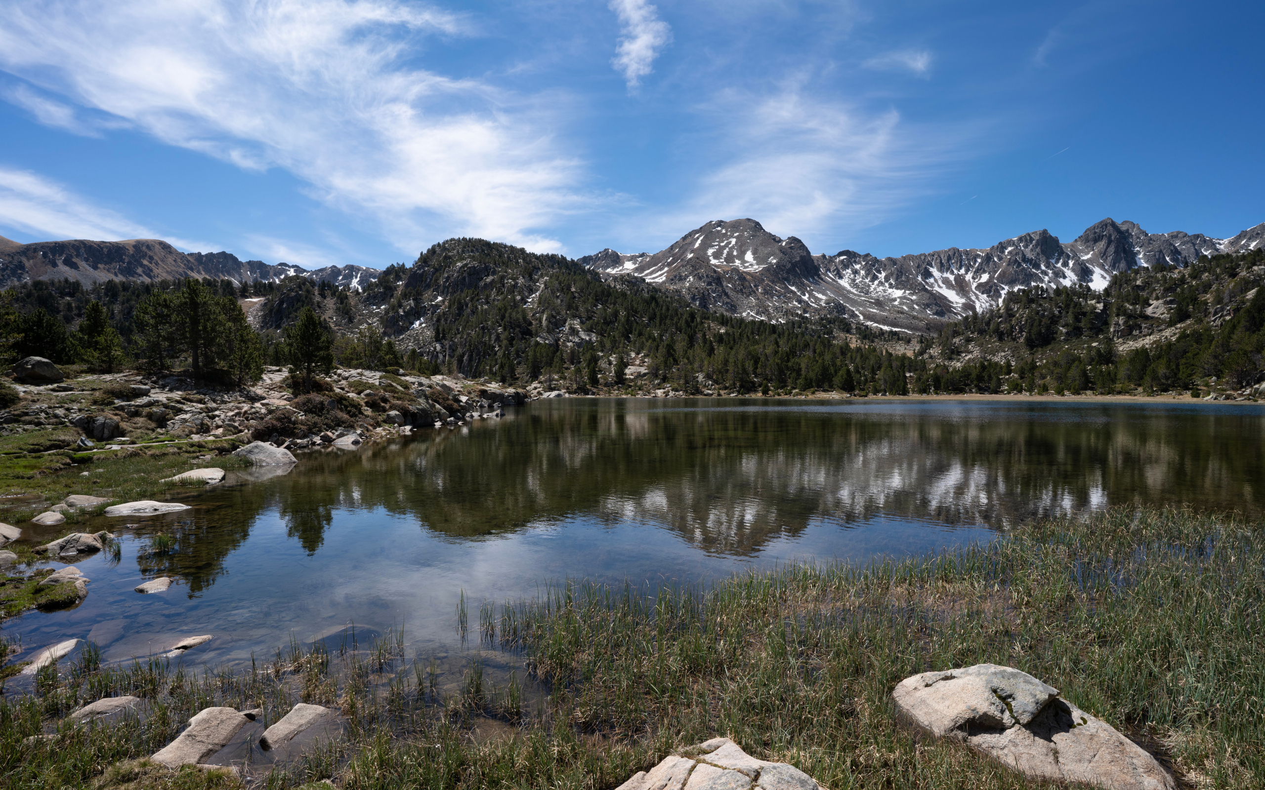 Горы отражаются в воде озера с большими камнями