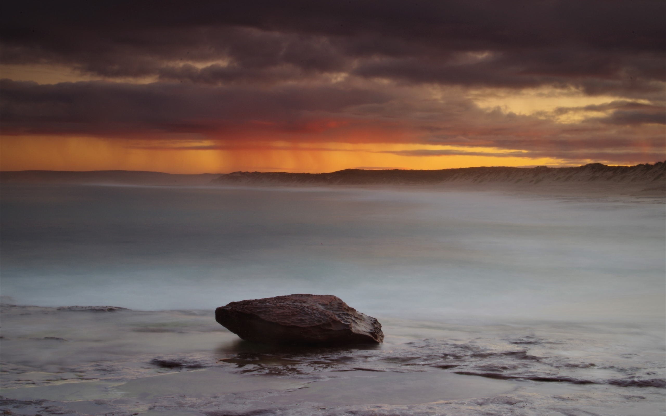 Большой камень в воде на фоне грозового неба в море