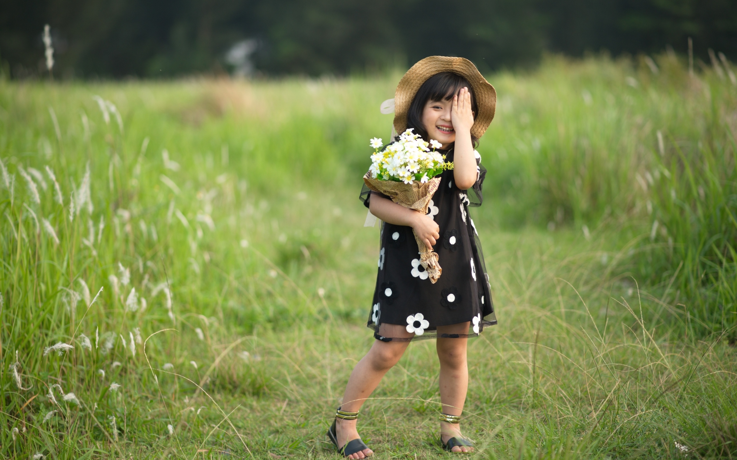 Девочка азиатка в шляпе с букетом цветов