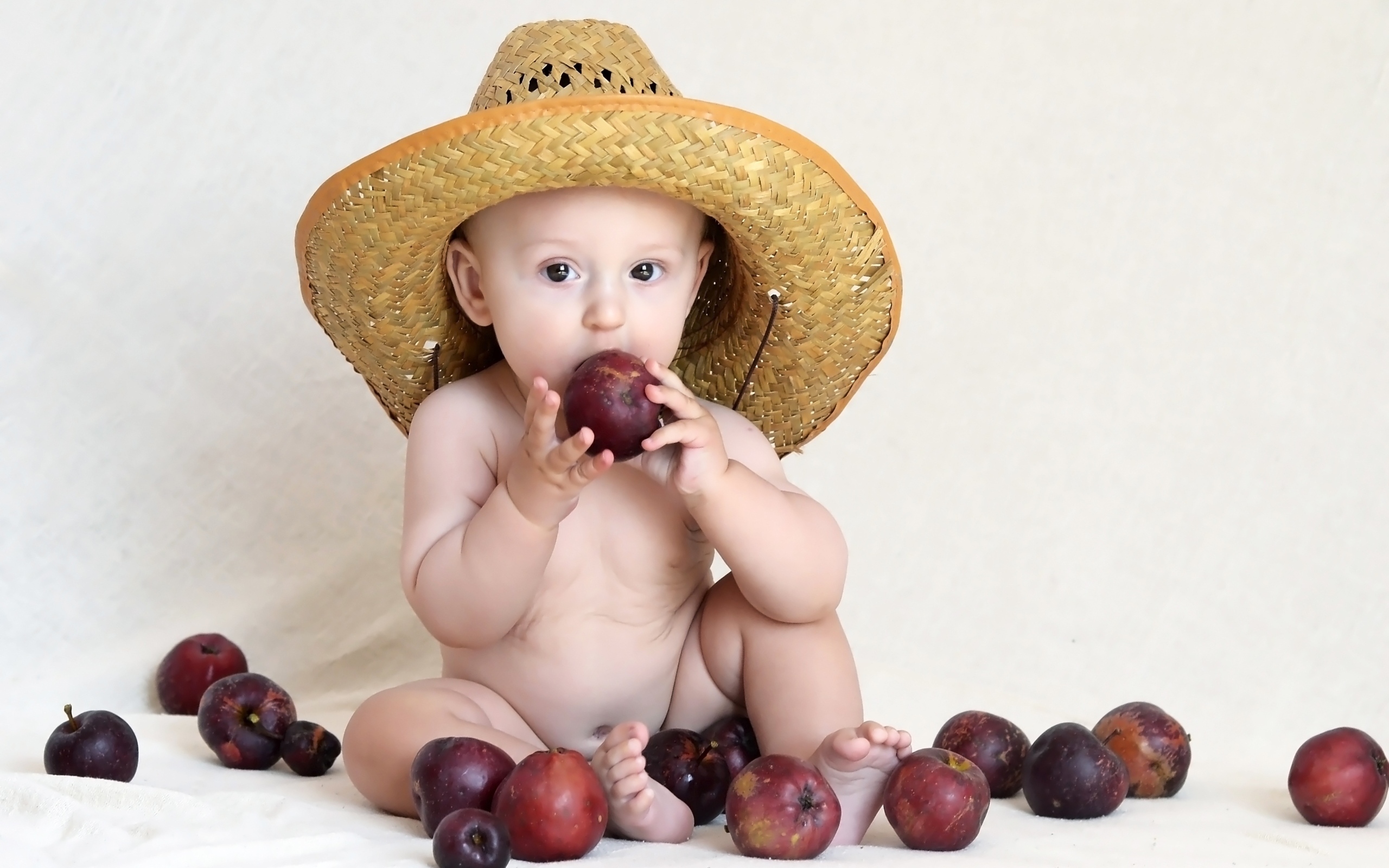 Малыш в шляпе грызет яблоки